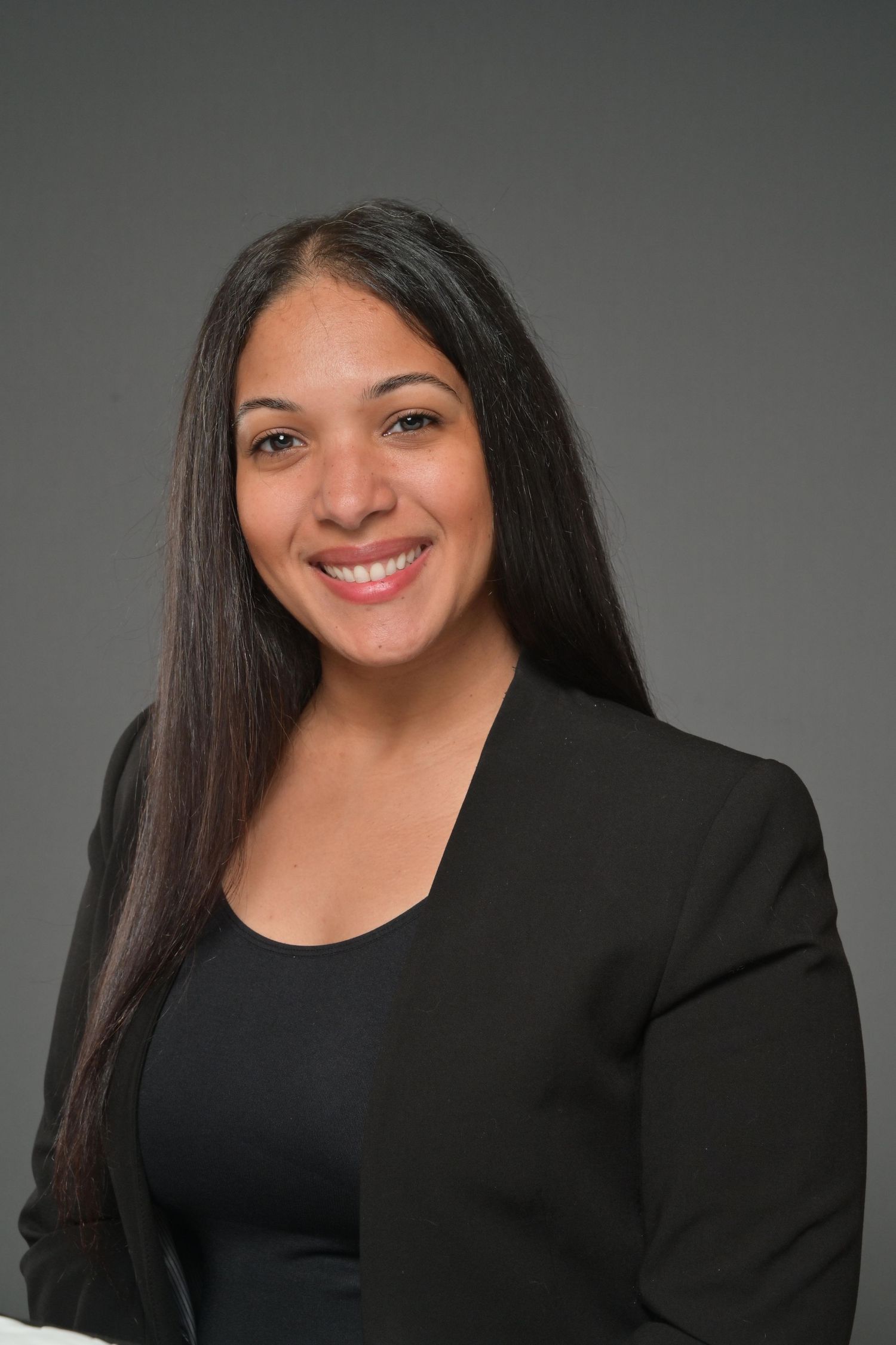 Professional woman with long dark hair smiling in a black blazer headshot.