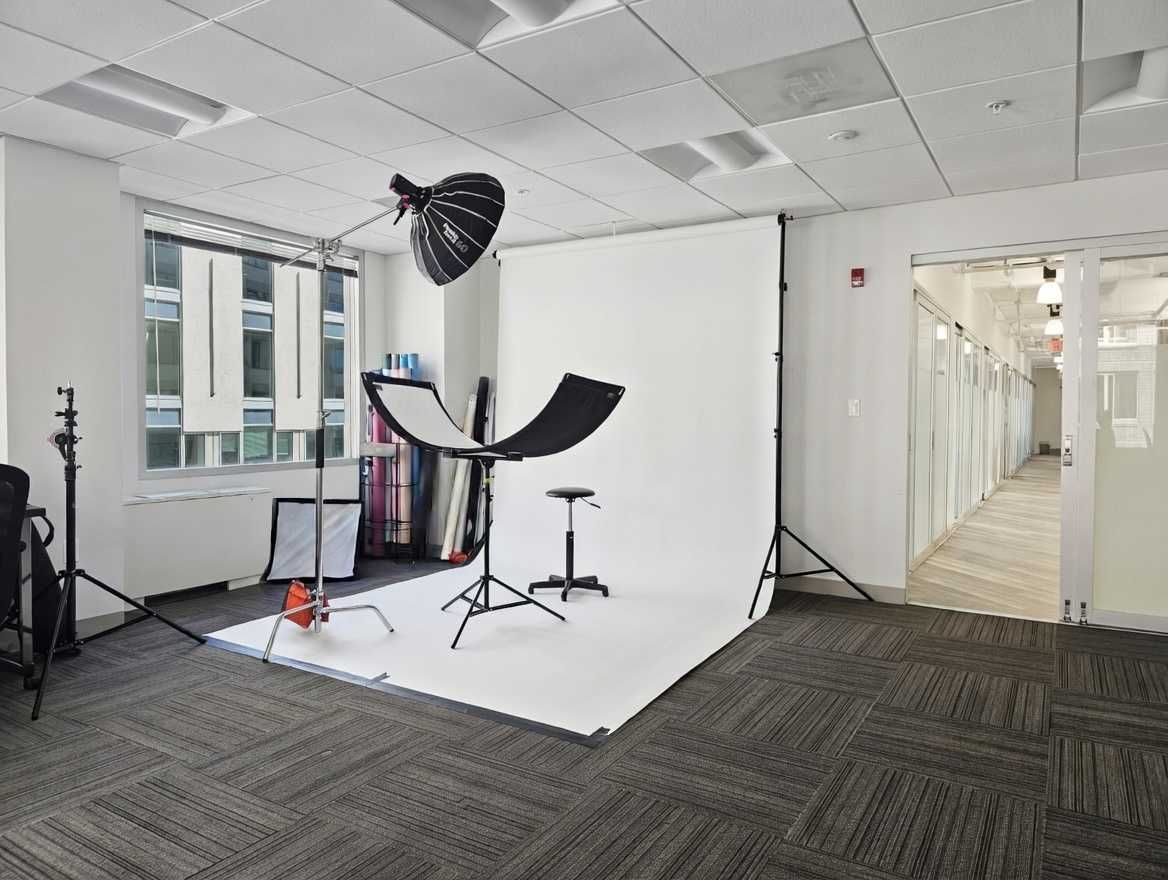 Professional photography studio setup with white backdrop and lighting equipment in an office.