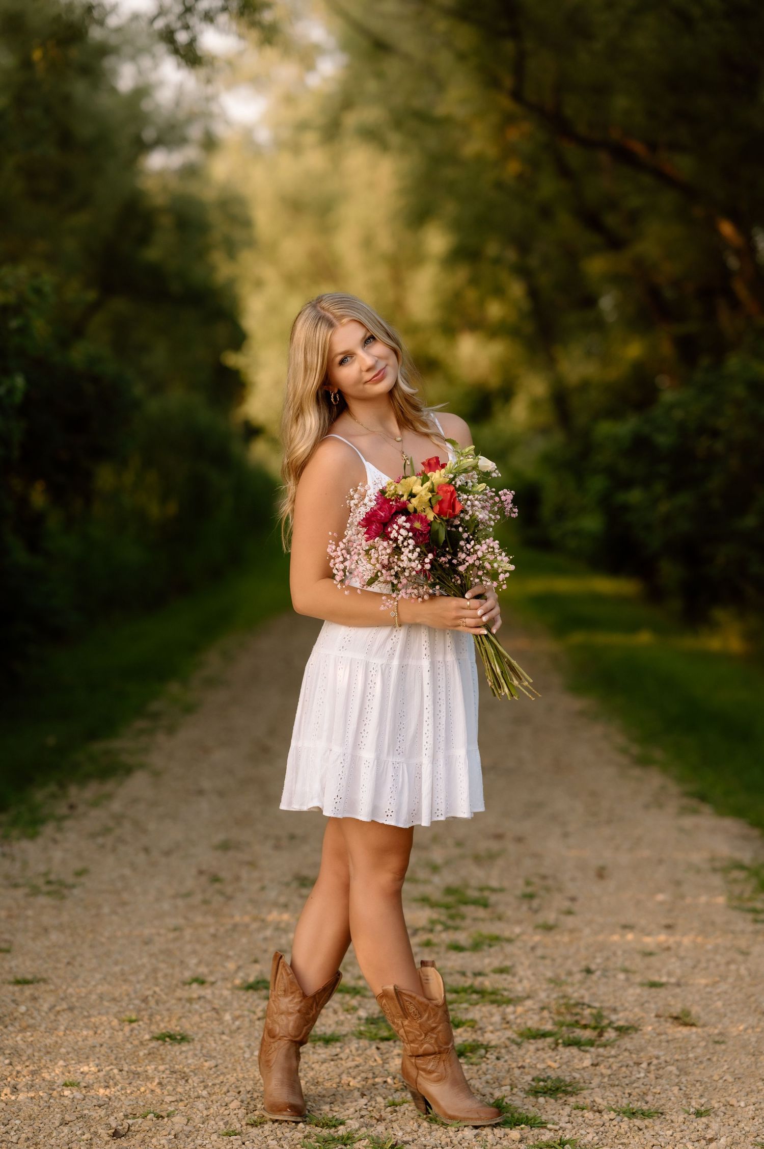 Summer portrait on dirt path with person holding colorful wildflower bouquet.