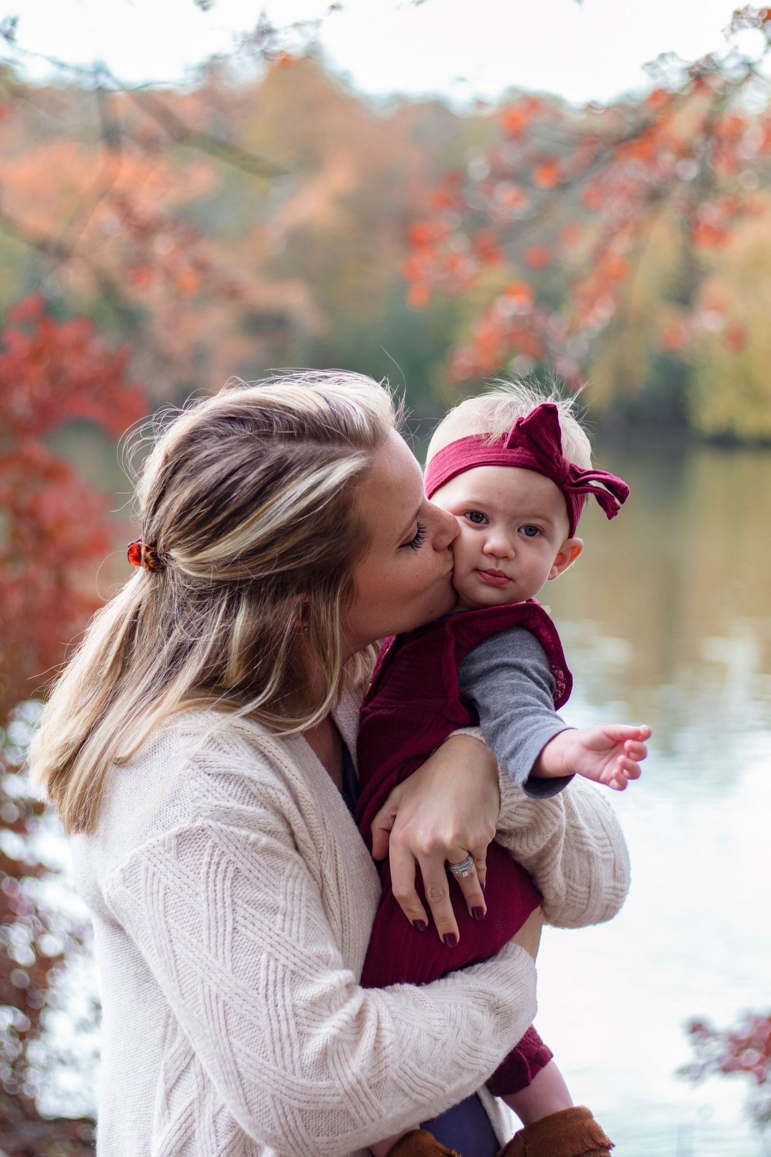 A tender moment of a mother kissing her baby in Elgin, IL, surrounded by natural beauty, capturing the pure love and bon