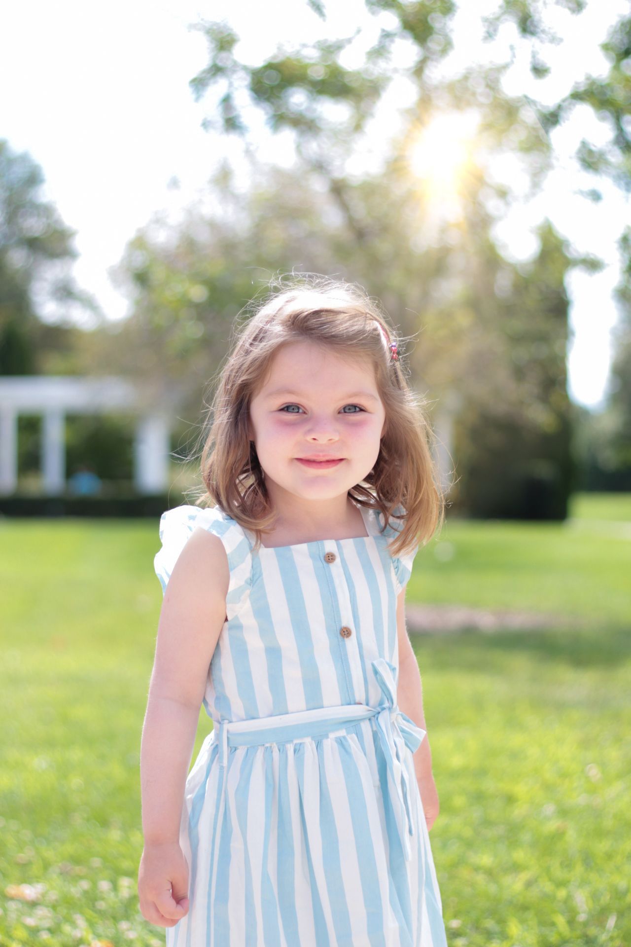 A vibrant and joyful little girl enjoying the outdoors on a sunny day in Geneva, IL, her face glowing with happiness as