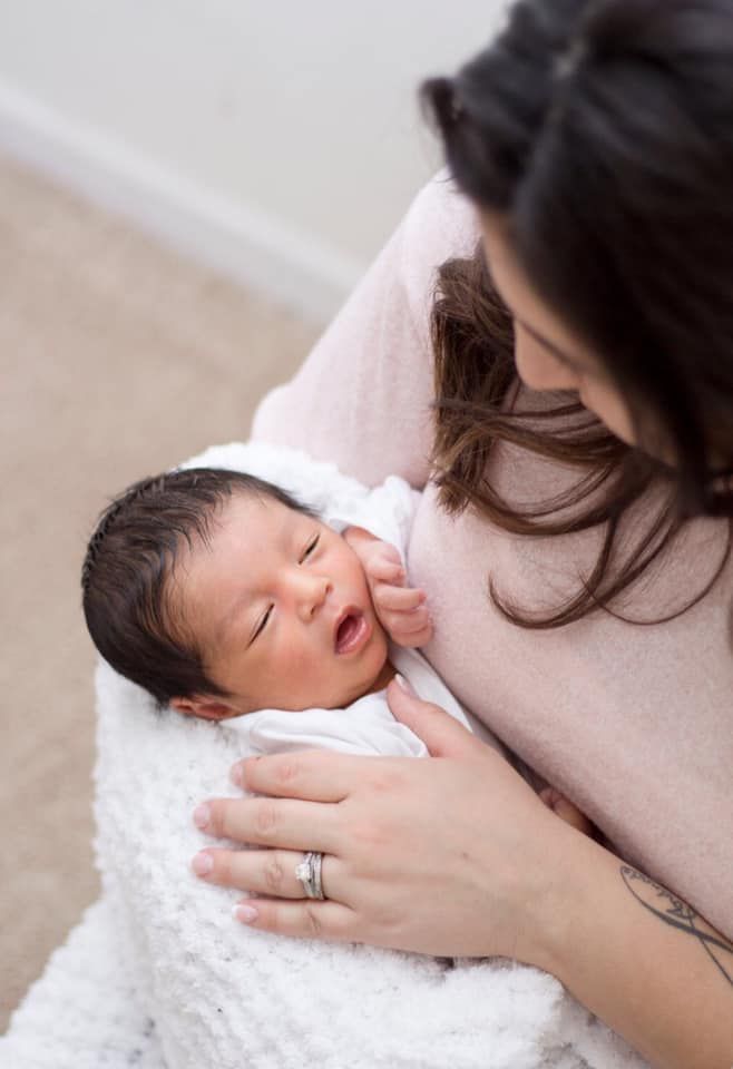 A heartfelt moment of a mother tenderly holding her newborn during an indoor lifestyle session in Schaumburg, IL, her ex