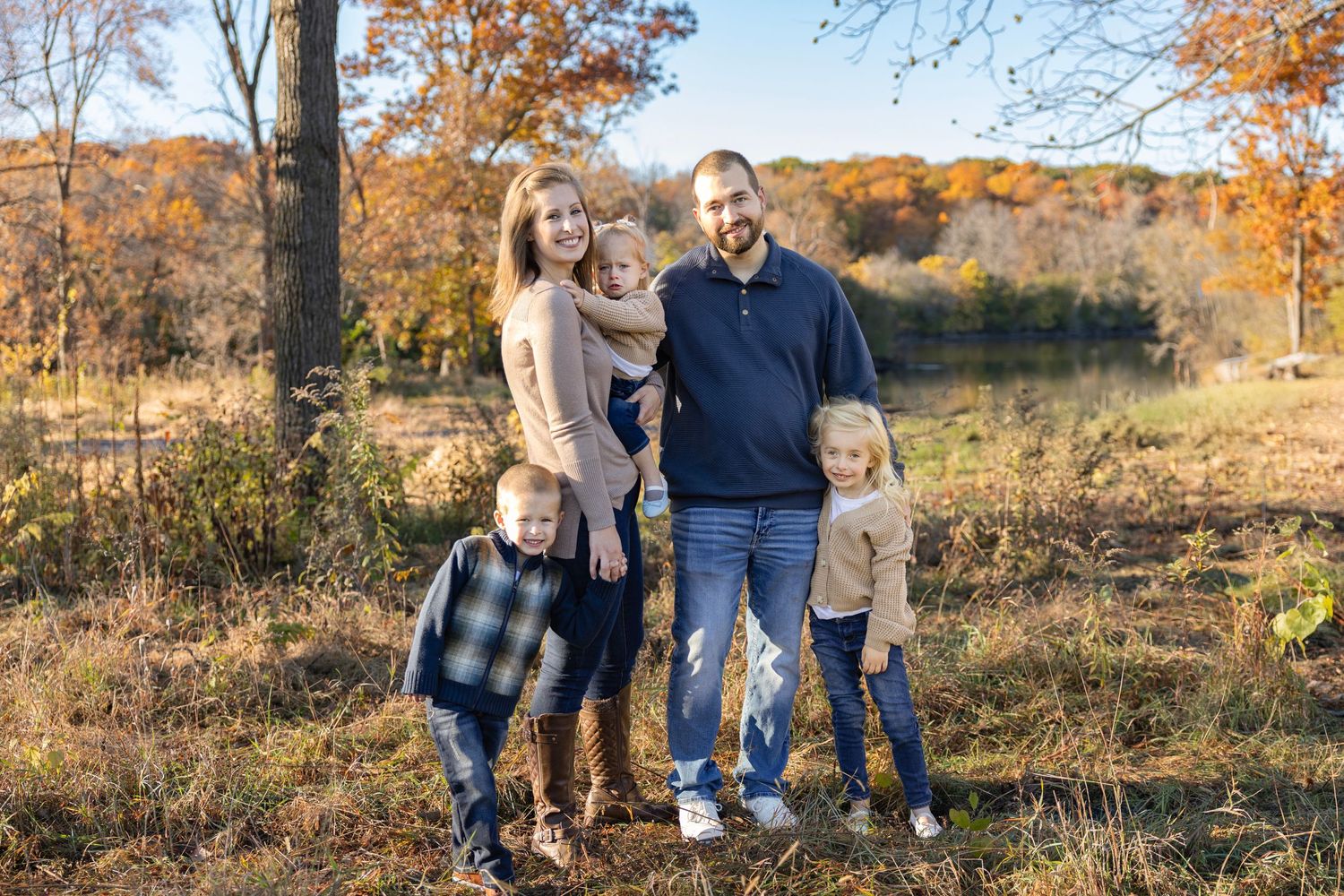 A heartwarming photoshoot of a small, growing family standing in front of the beautiful Fox River in South Elgin, surrou