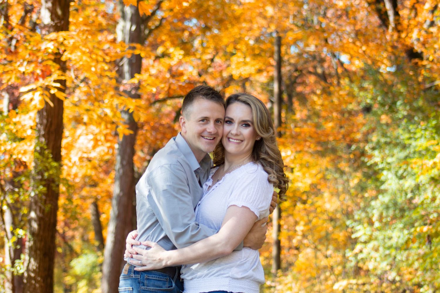 A vibrant fall photoshoot of a couple in love, surrounded by colorful autumn leaves and golden light, capturing their jo
