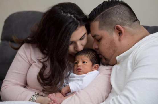 Parents lovingly holding their newborn during an indoor lifestyle session in Schaumburg, IL, sharing a tender moment as