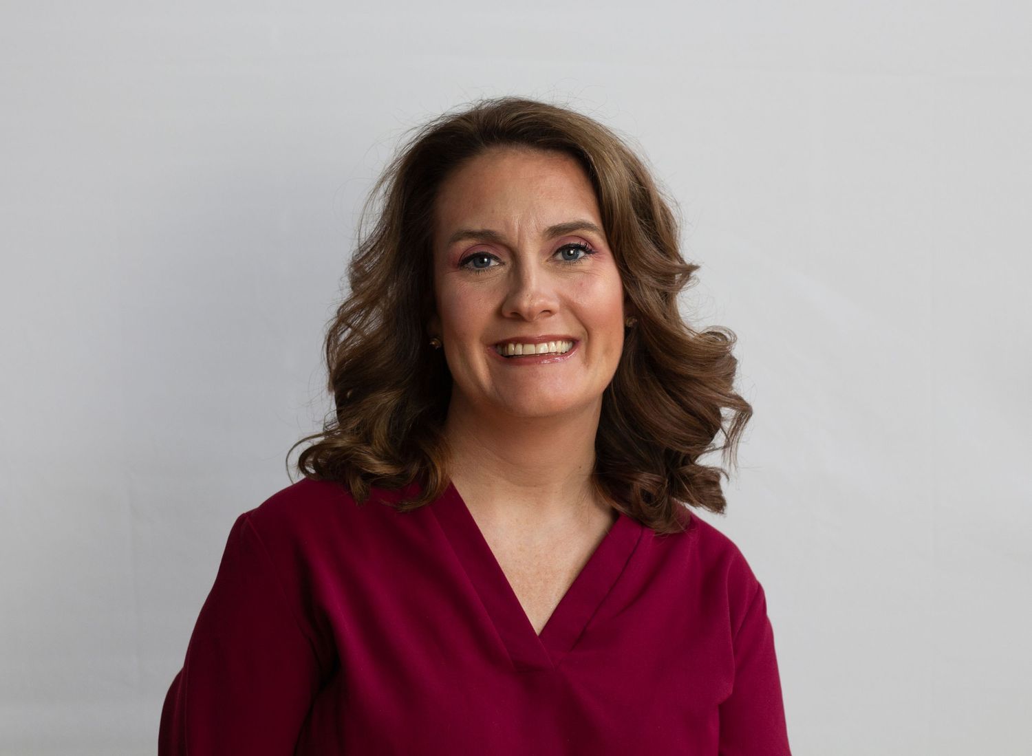 A professional corporate headshot featuring a poised individual with a confident expression, set against a sleek office