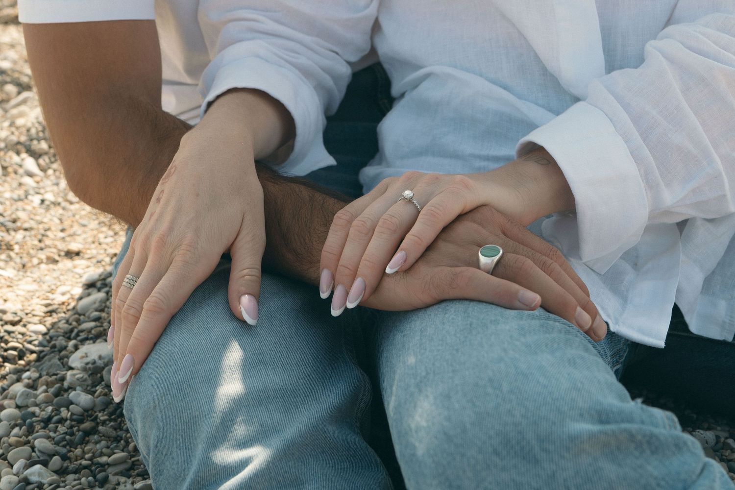 A close-up shot of hands resting on light blue denim jeans against a neutral background.