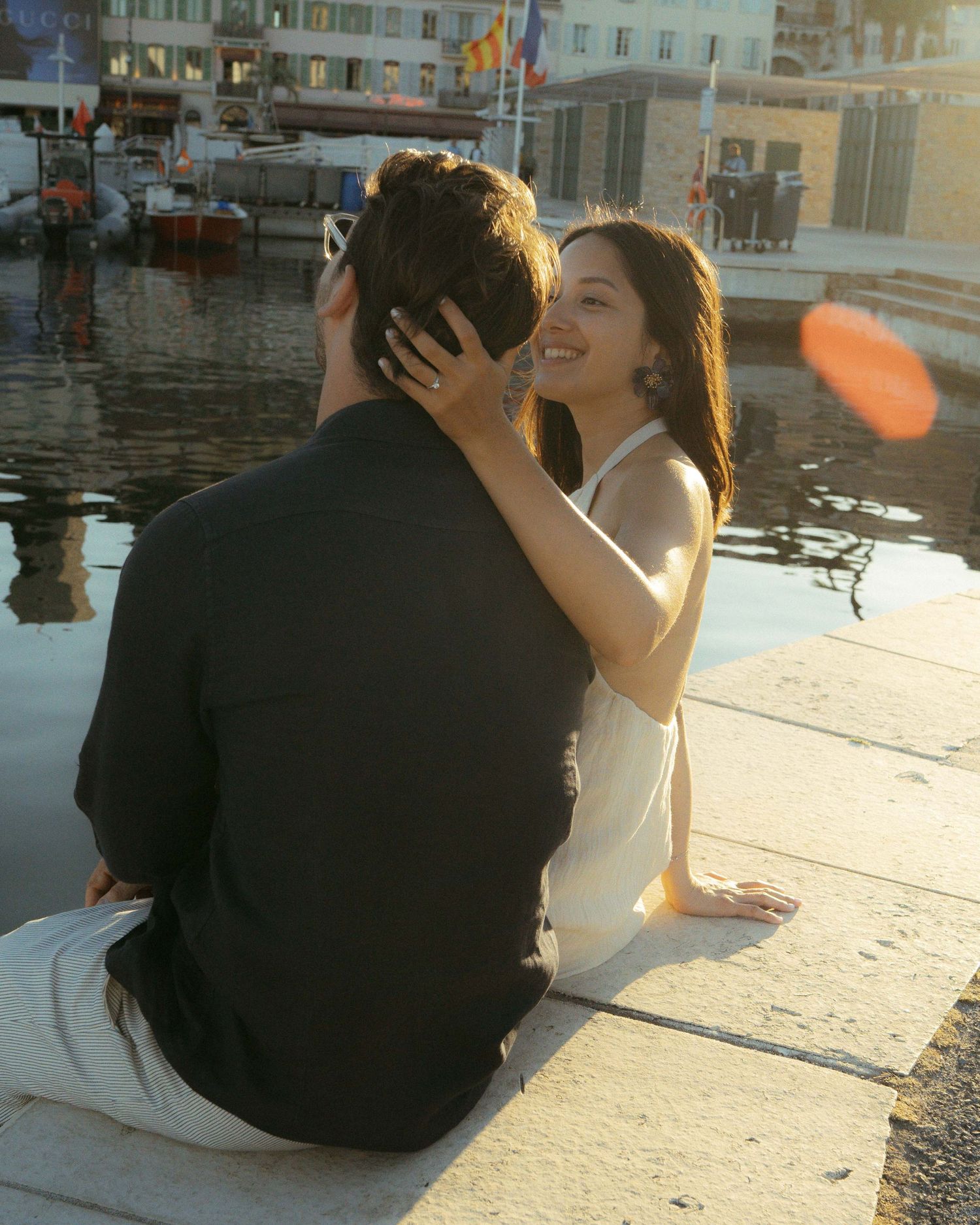 A couple shares an intimate moment while sitting by the water's edge during sunset.