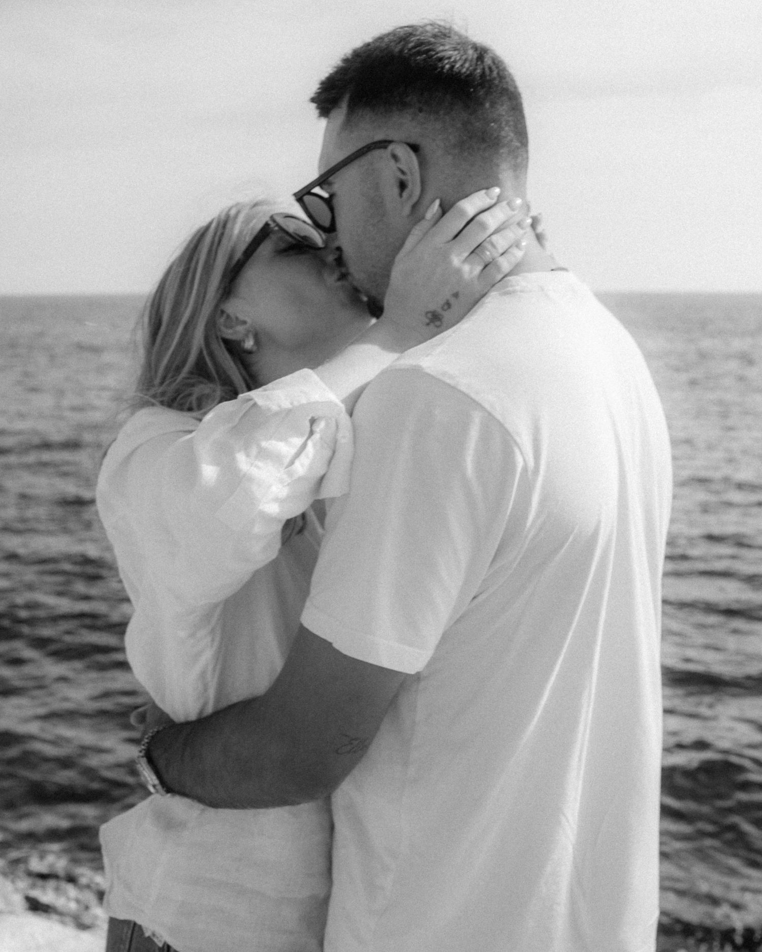 Black and white romantic couple photos by the ocean showing tender embraces at sunset.