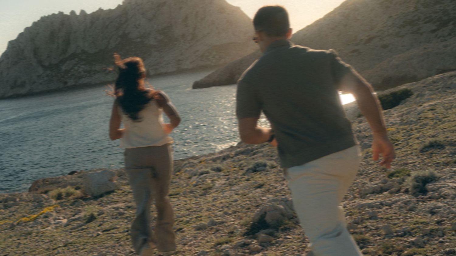People hiking along a rocky mountain trail at sunset with backpacks and hiking gear.