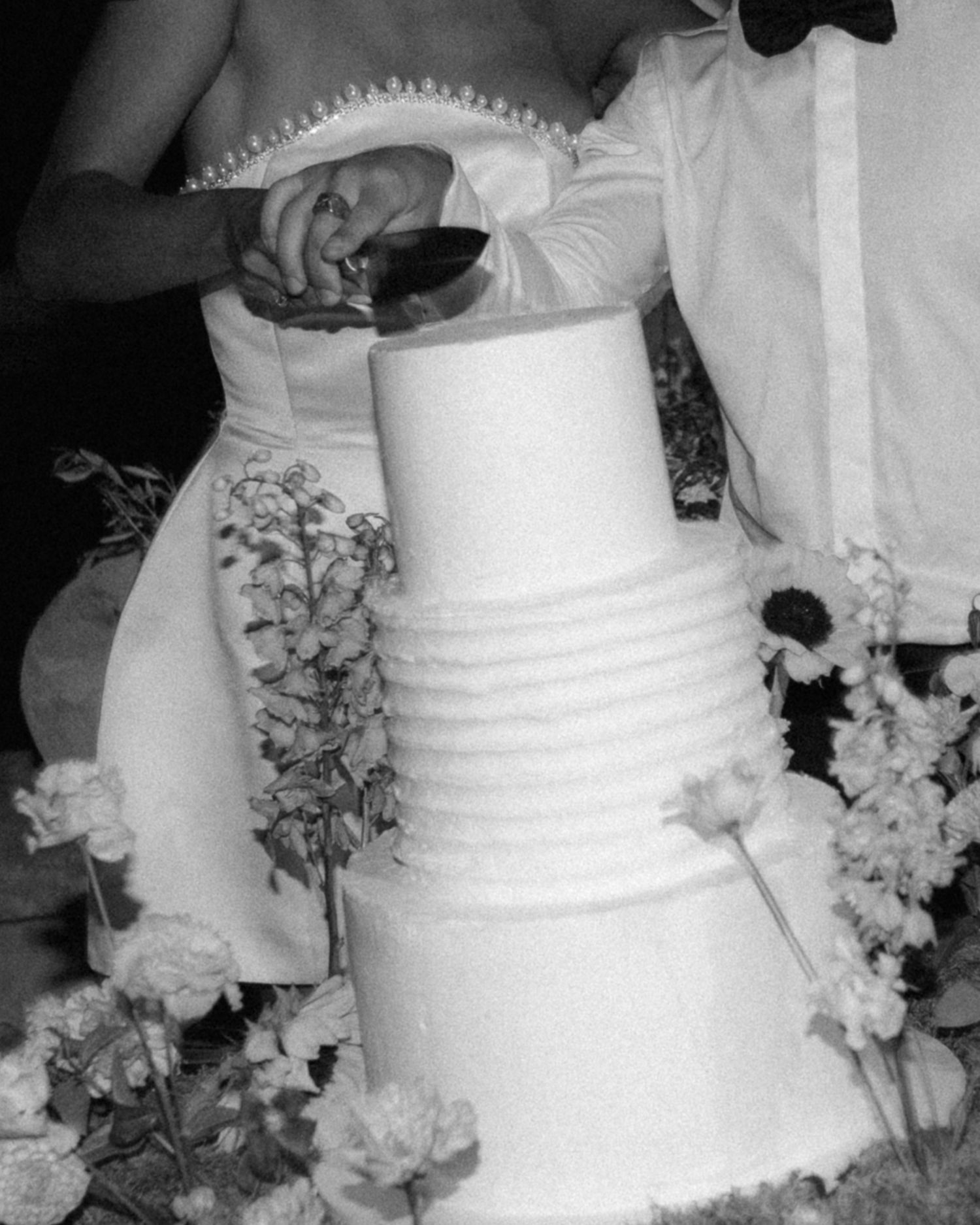 A traditional white wedding cake decorated with delicate floral arrangements and horizontal textured stripes.