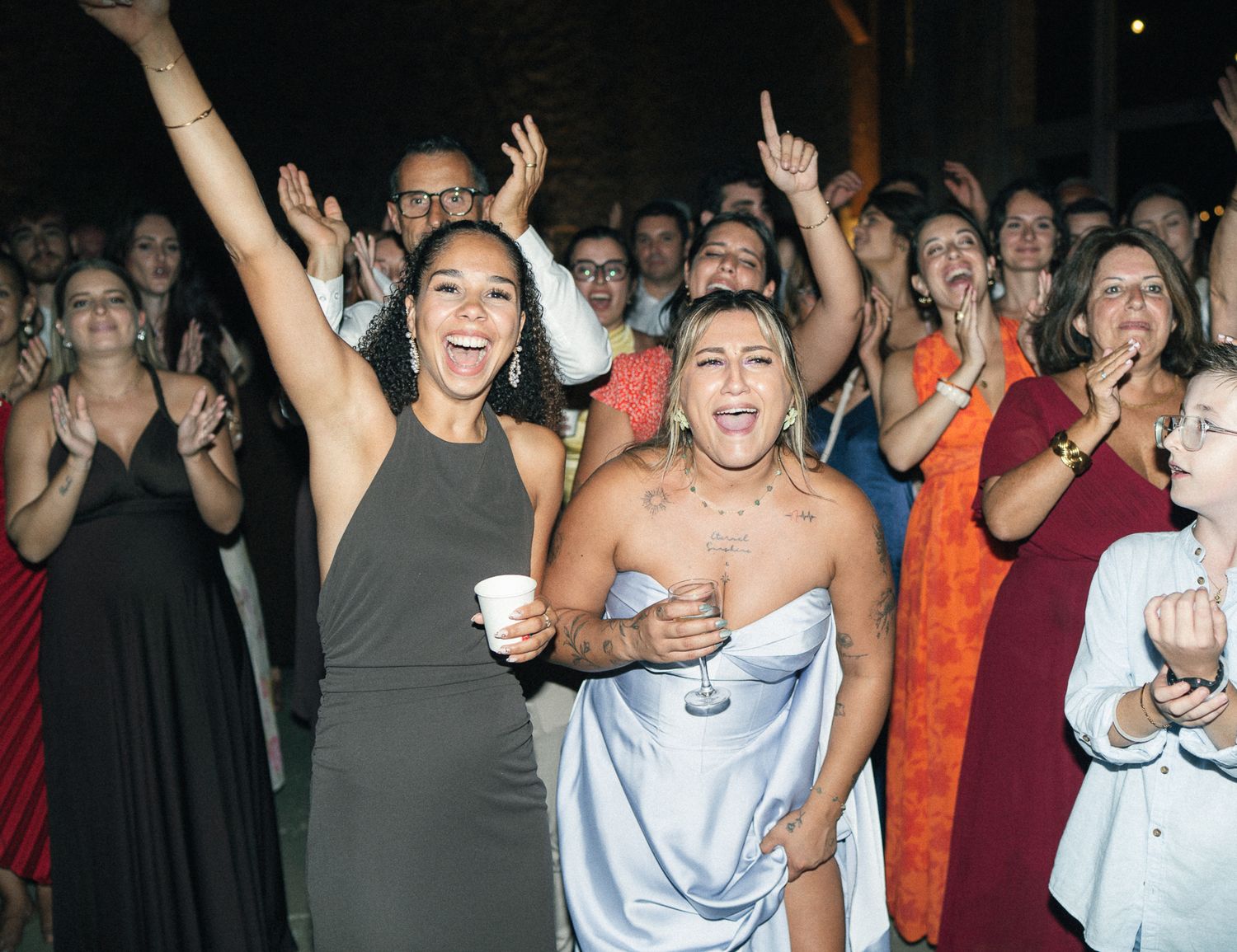 Joyful wedding guests dancing and celebrating at a lively outdoor wedding reception party.