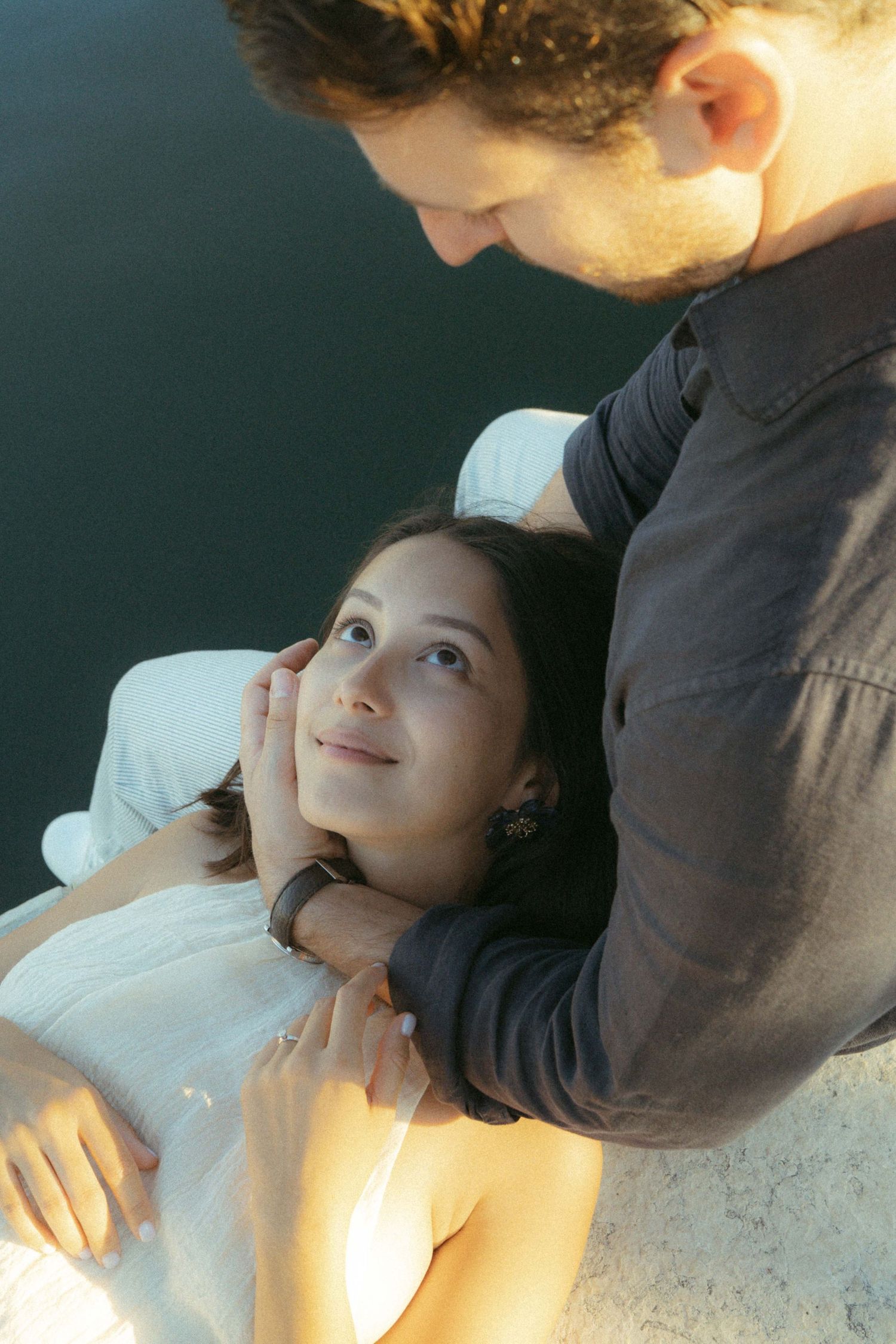 A person lies down while someone gently touches their face in a series of connected artistic photographs.