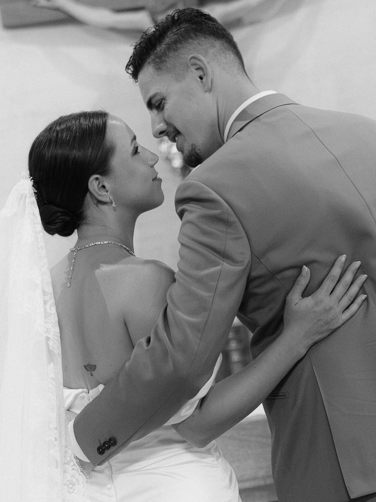 Black and white wedding photo of bride and groom sharing a romantic dance, gazing at each other lovingly.