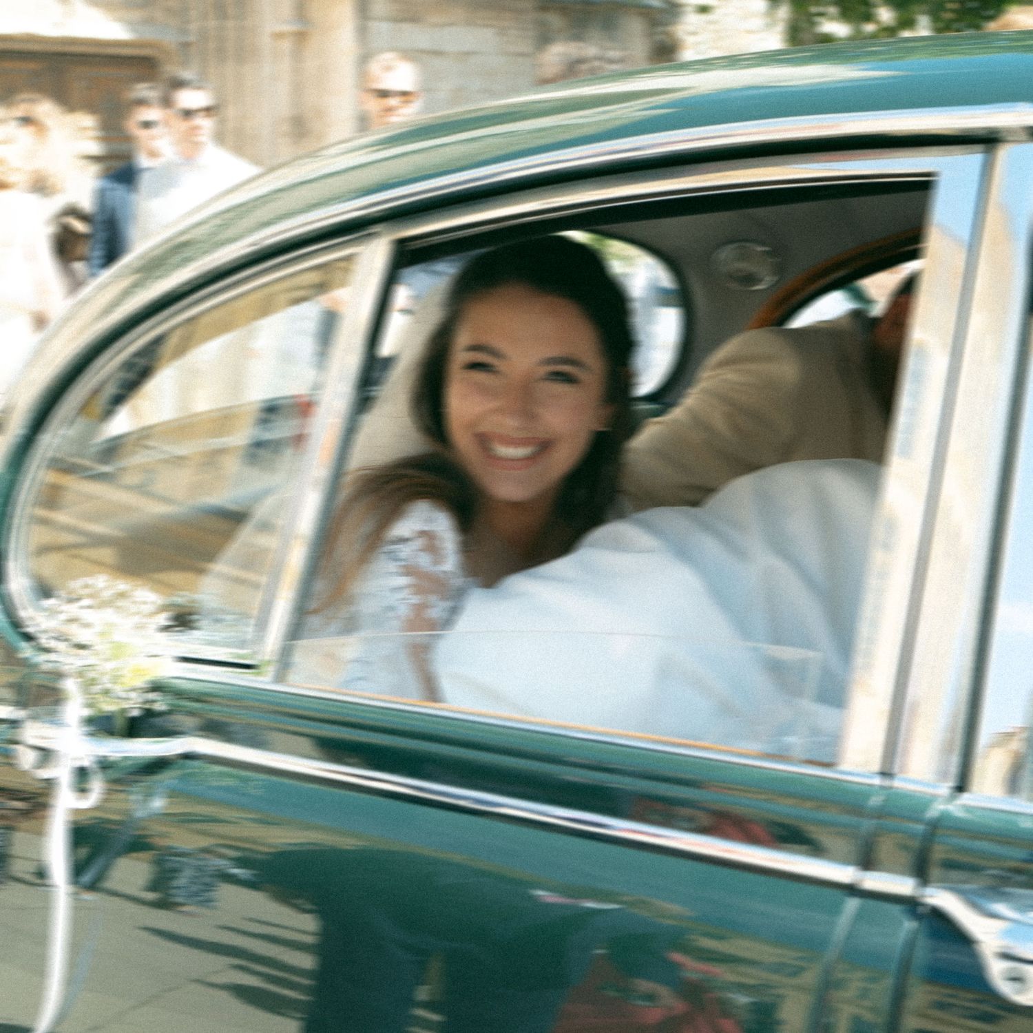 People enjoying a ride in a classic vintage turquoise car with chrome details on a sunny day.