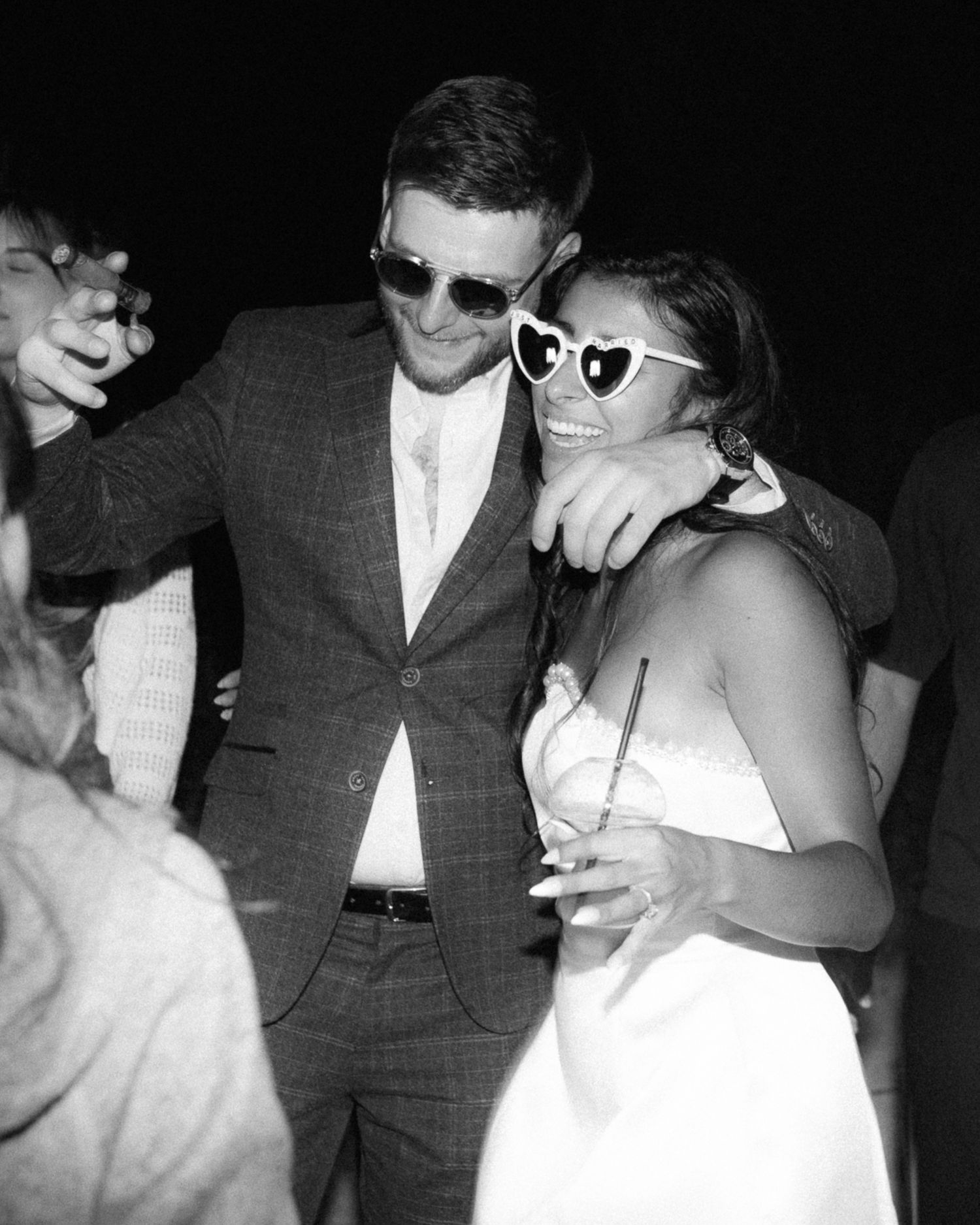 Wedding couple and guests wearing sunglasses pose together in black and white photo series.