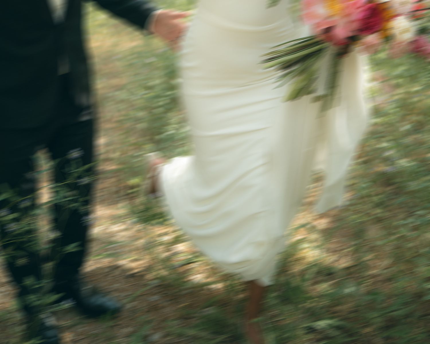 A dreamy motion-blurred photo of a person in a white dress walking through a garden with soft natural lighting.