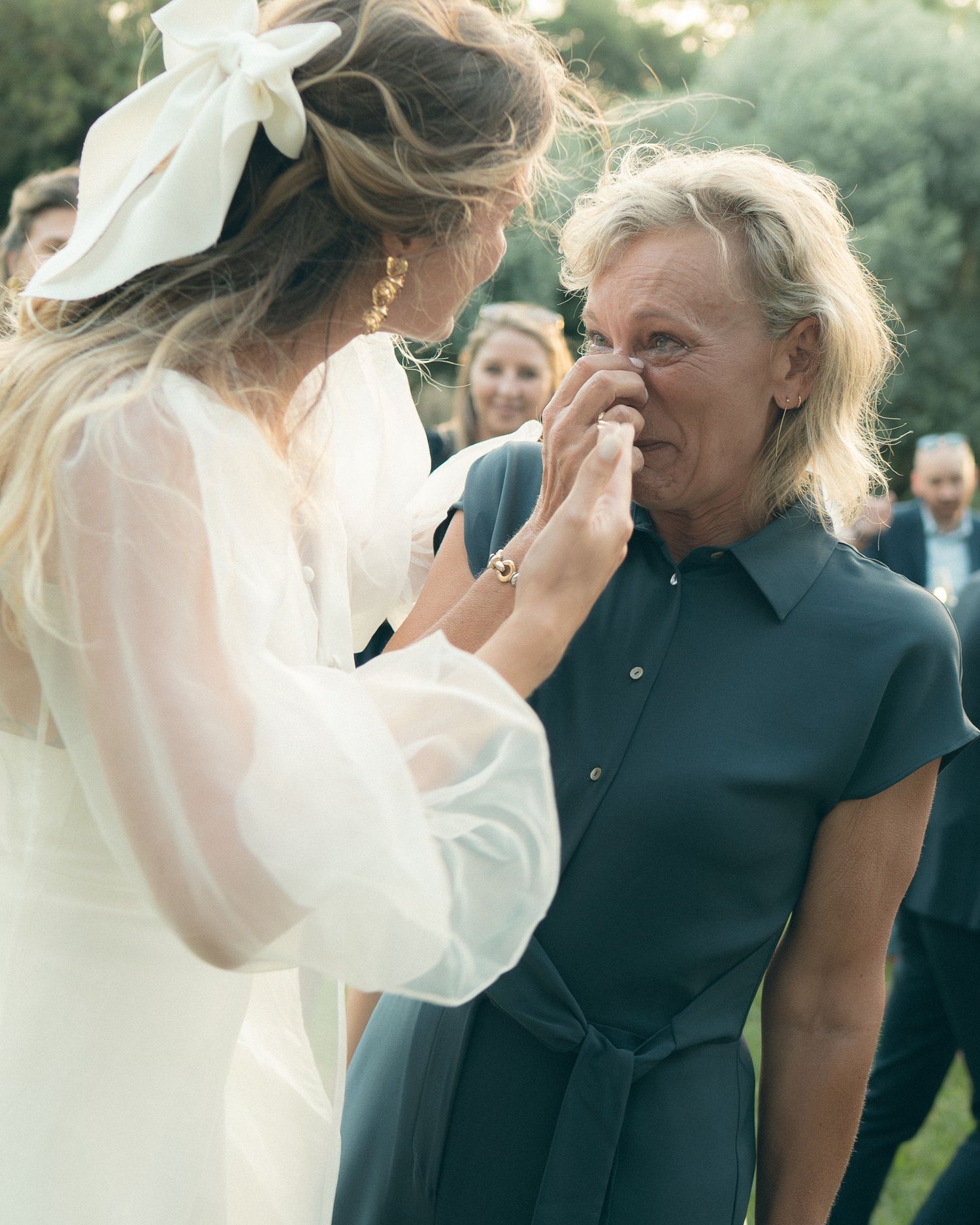 Candid wedding photography capturing emotional moments in an outdoor setting.