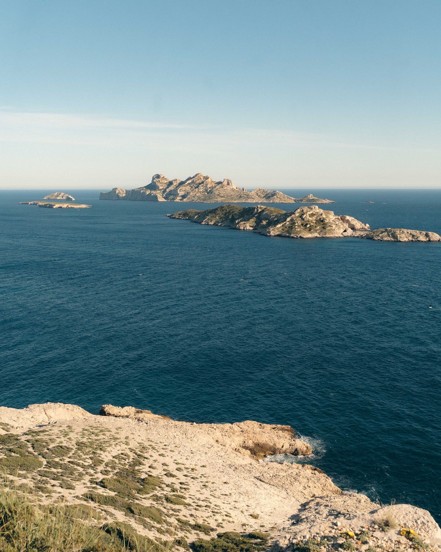 Rocky coastline of Marseille's Calanques National Park with deep blue Mediterranean waters and rugged limestone cliffs.