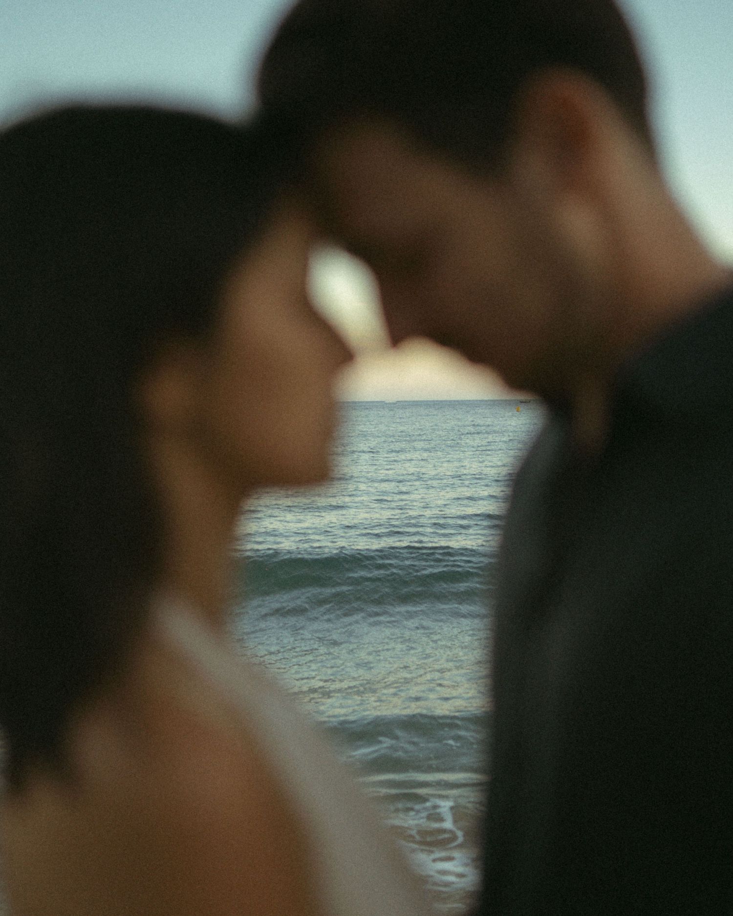 Out of focus silhouettes against a blurred ocean background create a dreamy atmospheric scene.