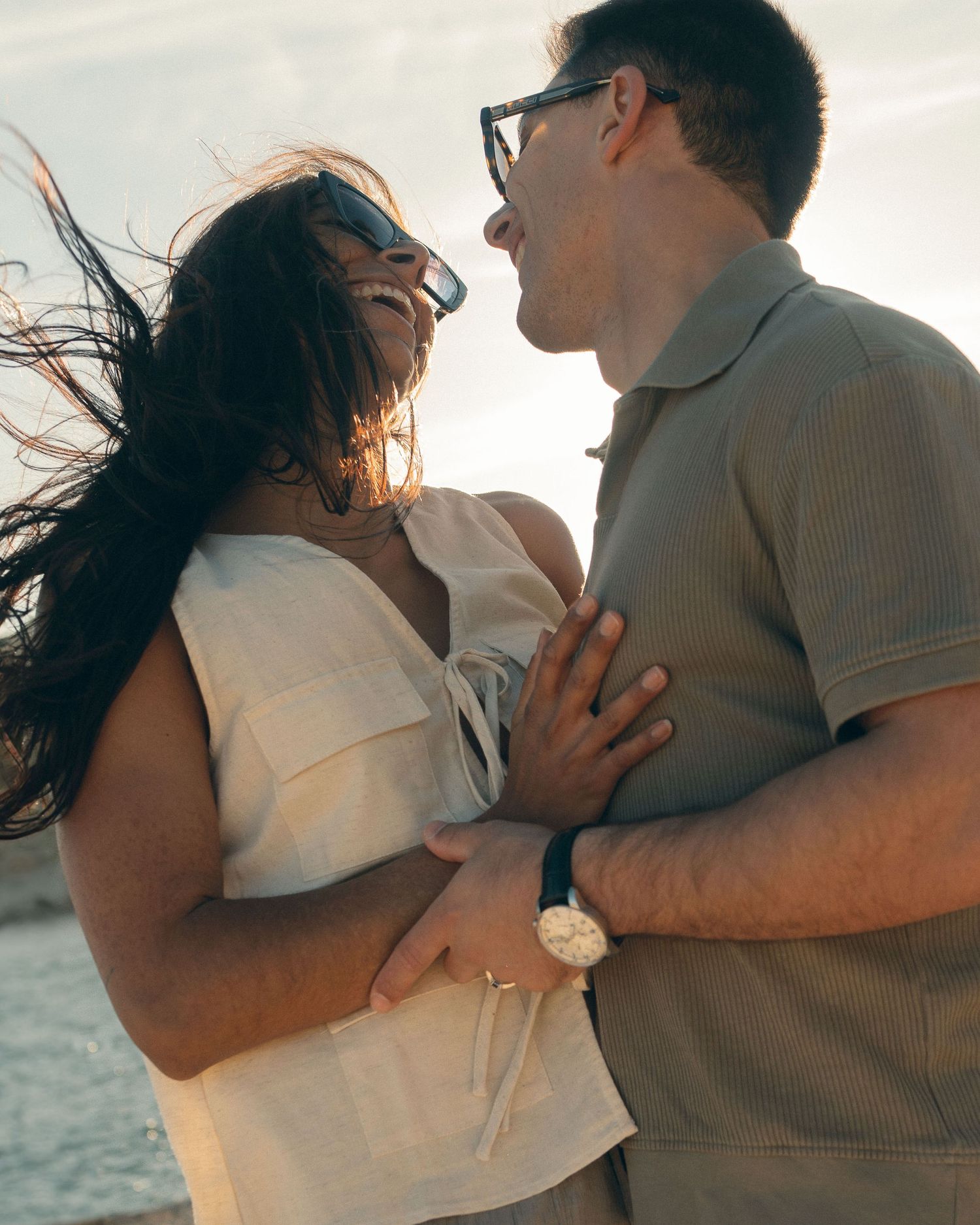 A romantic couple embraces by the ocean during golden hour in a series of intimate candid moments.
