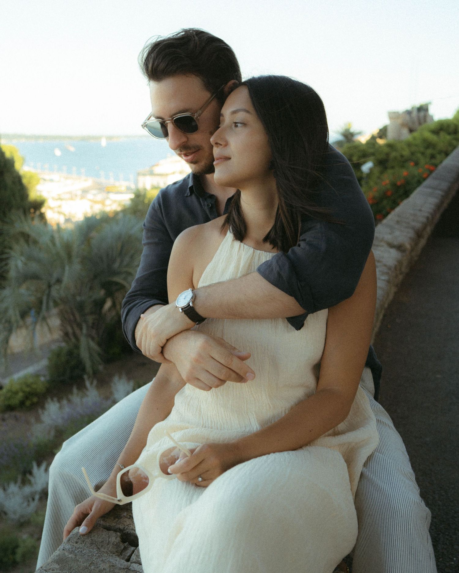 A couple shares an intimate moment while sitting together outdoors at sunset overlooking a scenic view.