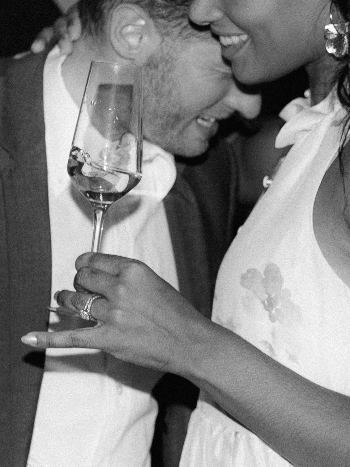 Black and white photo of a couple sharing a romantic moment at a party, woman holding a wine glass.