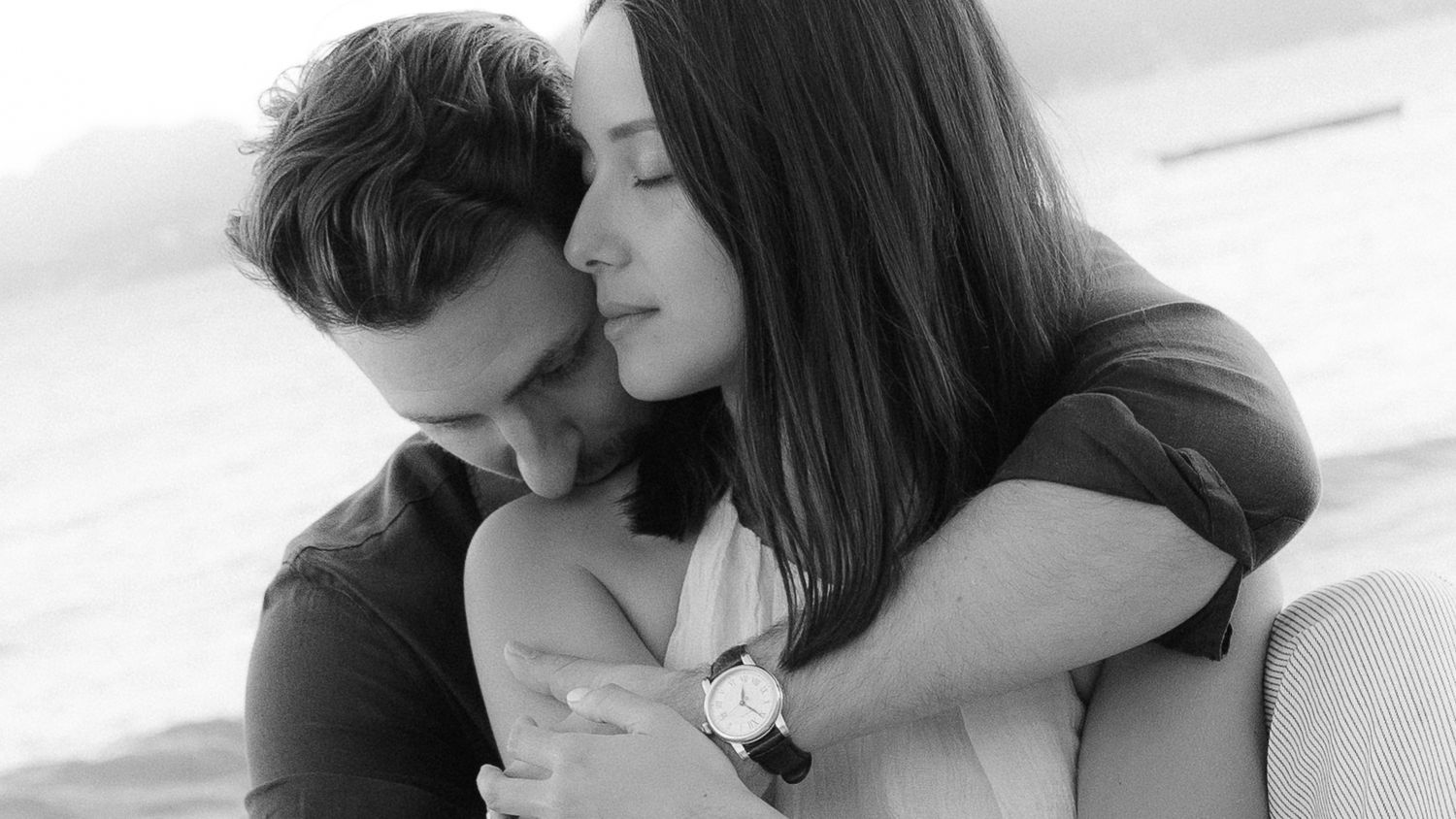 A tender black and white portrait of an intimate embrace between two people sharing a gentle moment together.