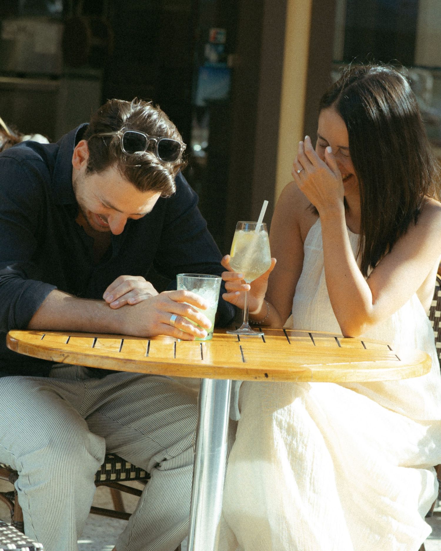 People sitting at a long wooden table working on crafts or writing activities together in a bright indoor space.