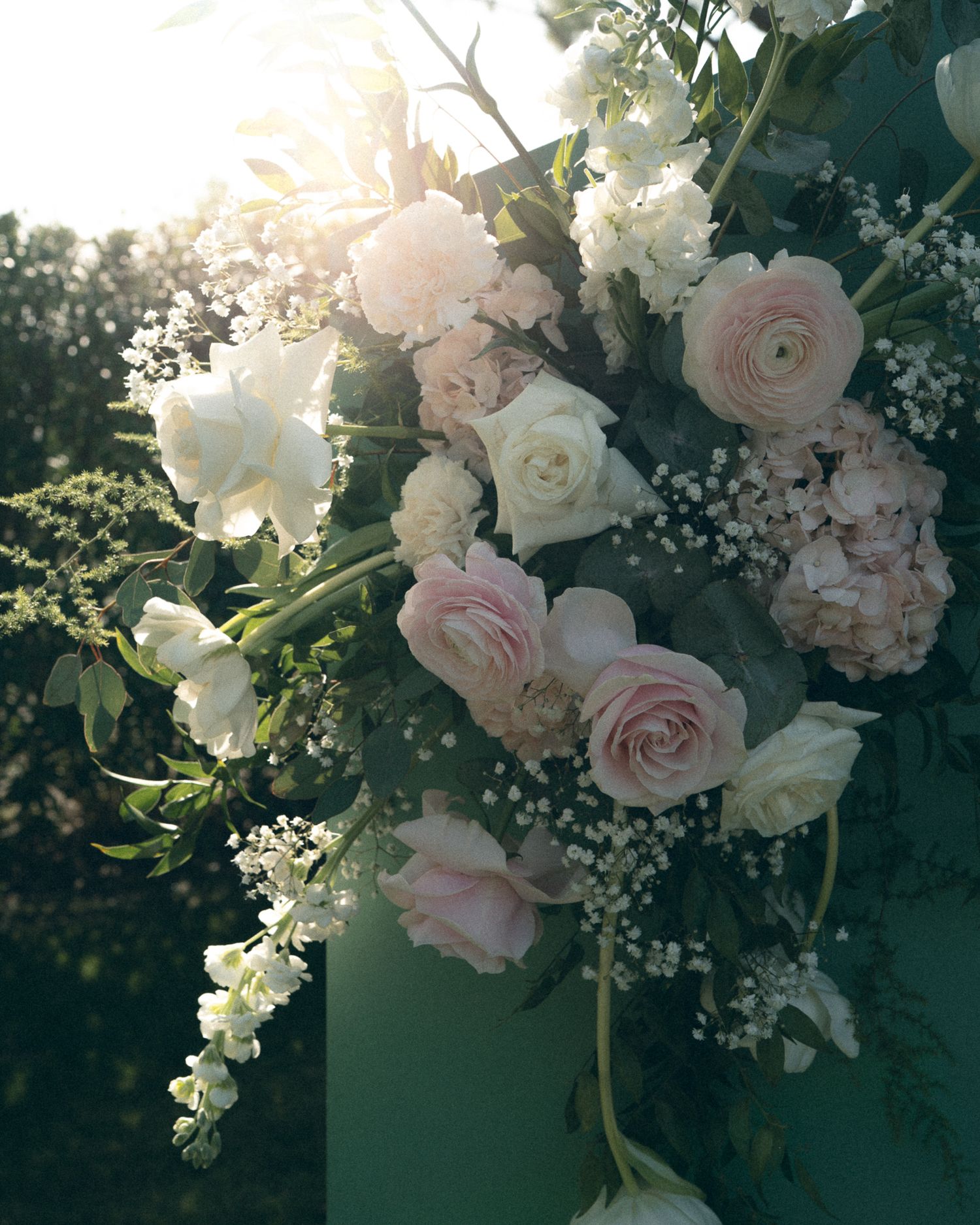 Elegant floral arrangement with pink and white roses, baby's breath, and delicate blooms in sunset light.