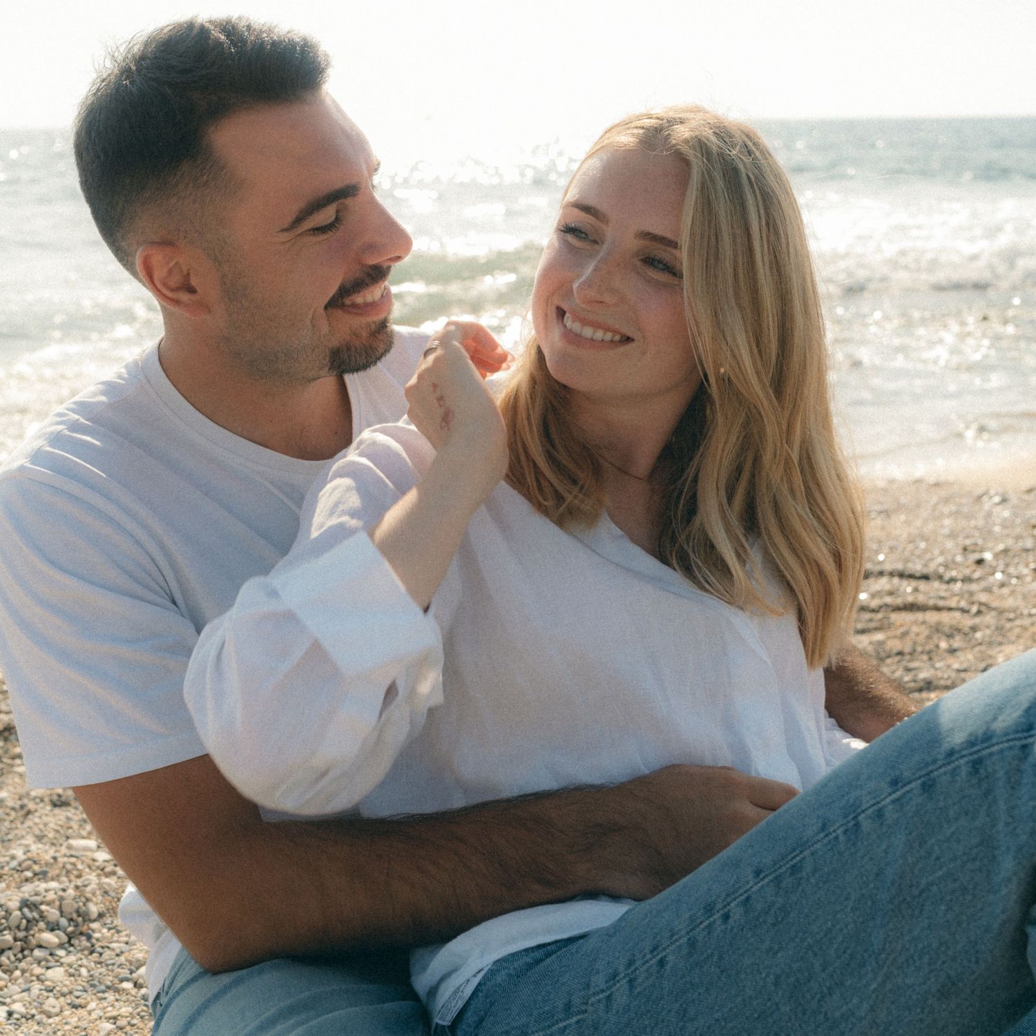 Couple sharing intimate moments on a beach during golden hour, shown in a series of candid photographs.