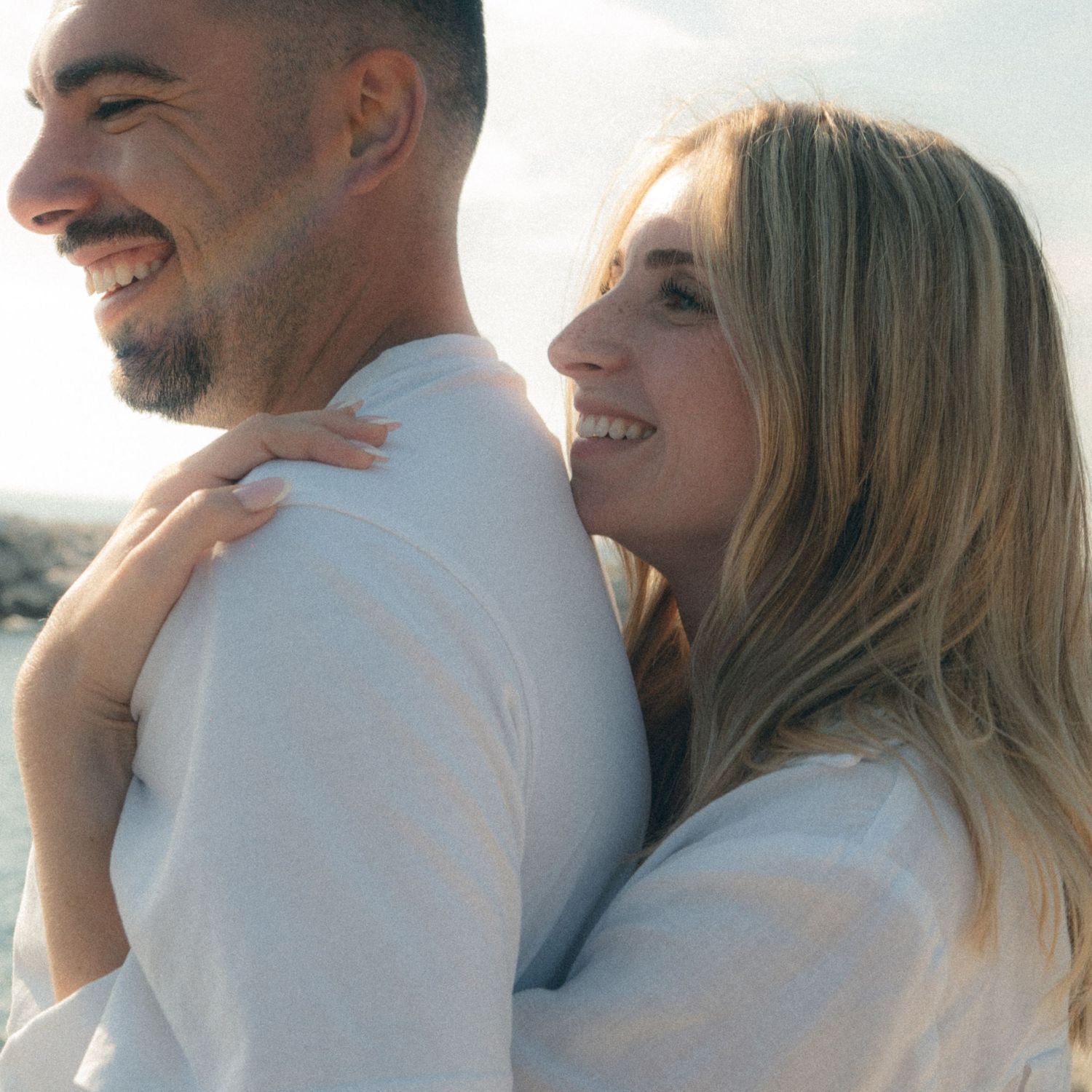 Couple in white outfits sharing intimate moments in a romantic outdoor photoshoot sequence.