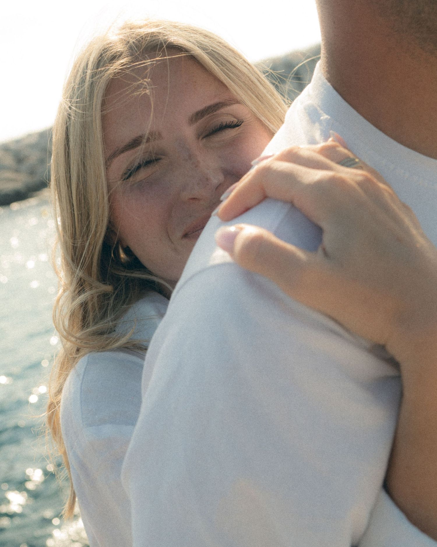 A couple shares a romantic kiss while enjoying a sunny day by the sparkling water.