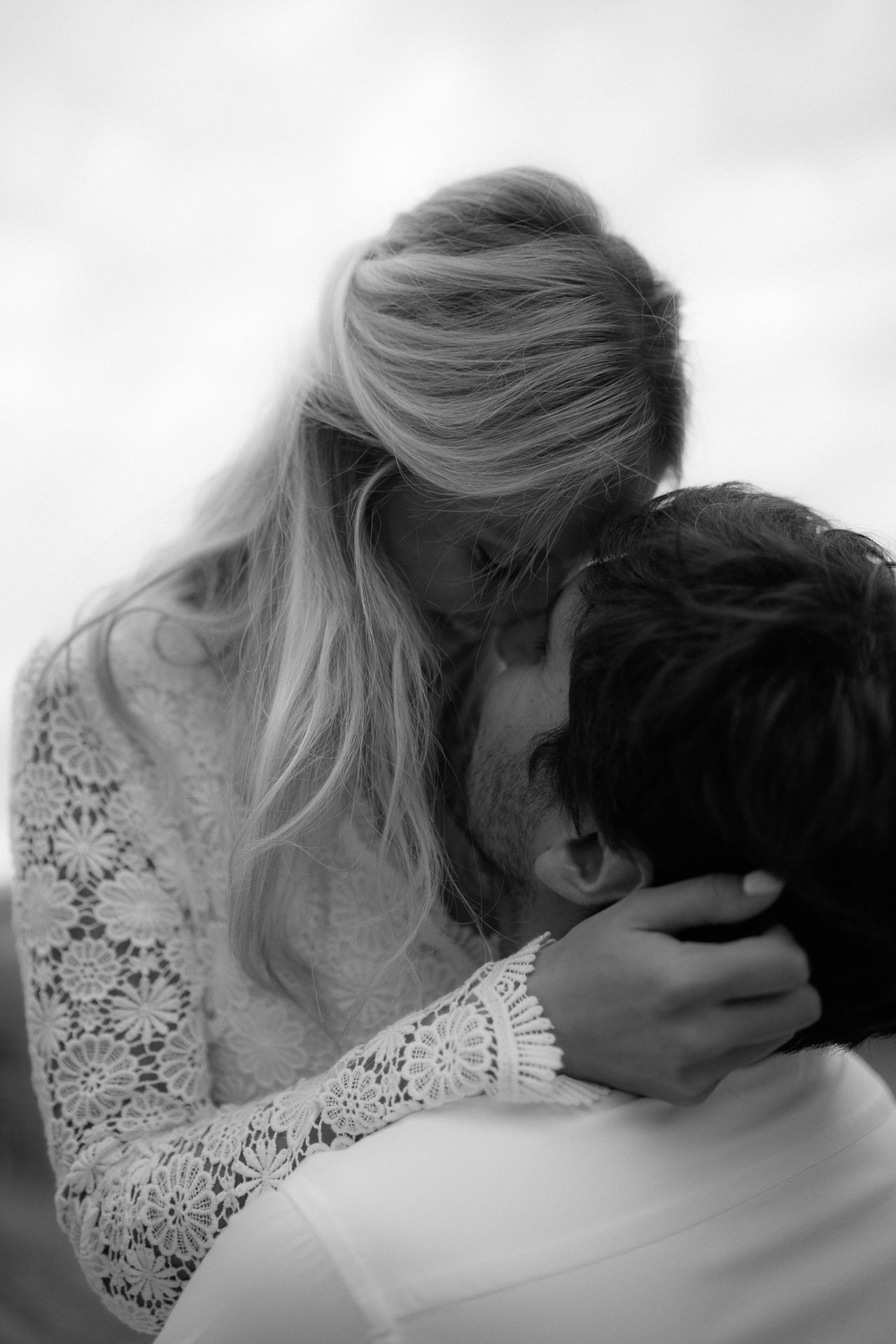 A romantic black and white photo shows an intimate embrace between a couple, with the bride wearing a lace sleeve dress.