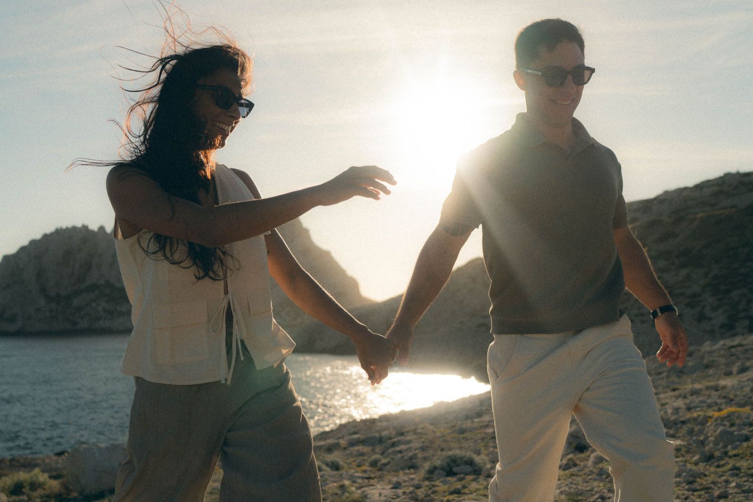 Two people dancing together on a beach at sunset with mountains in the background.