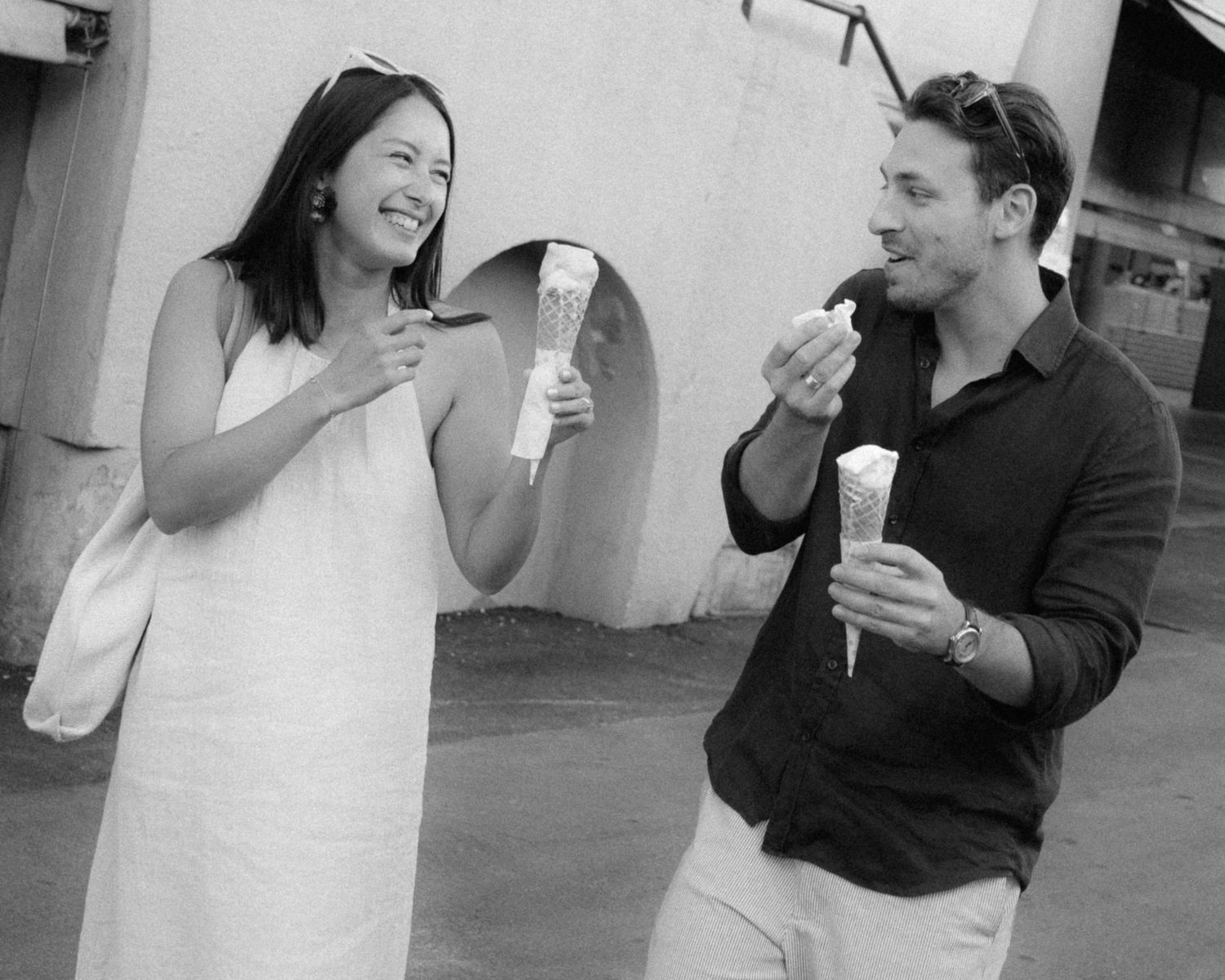 Black and white photo sequence showing a couple laughing and interacting playfully in a casual outdoor setting.