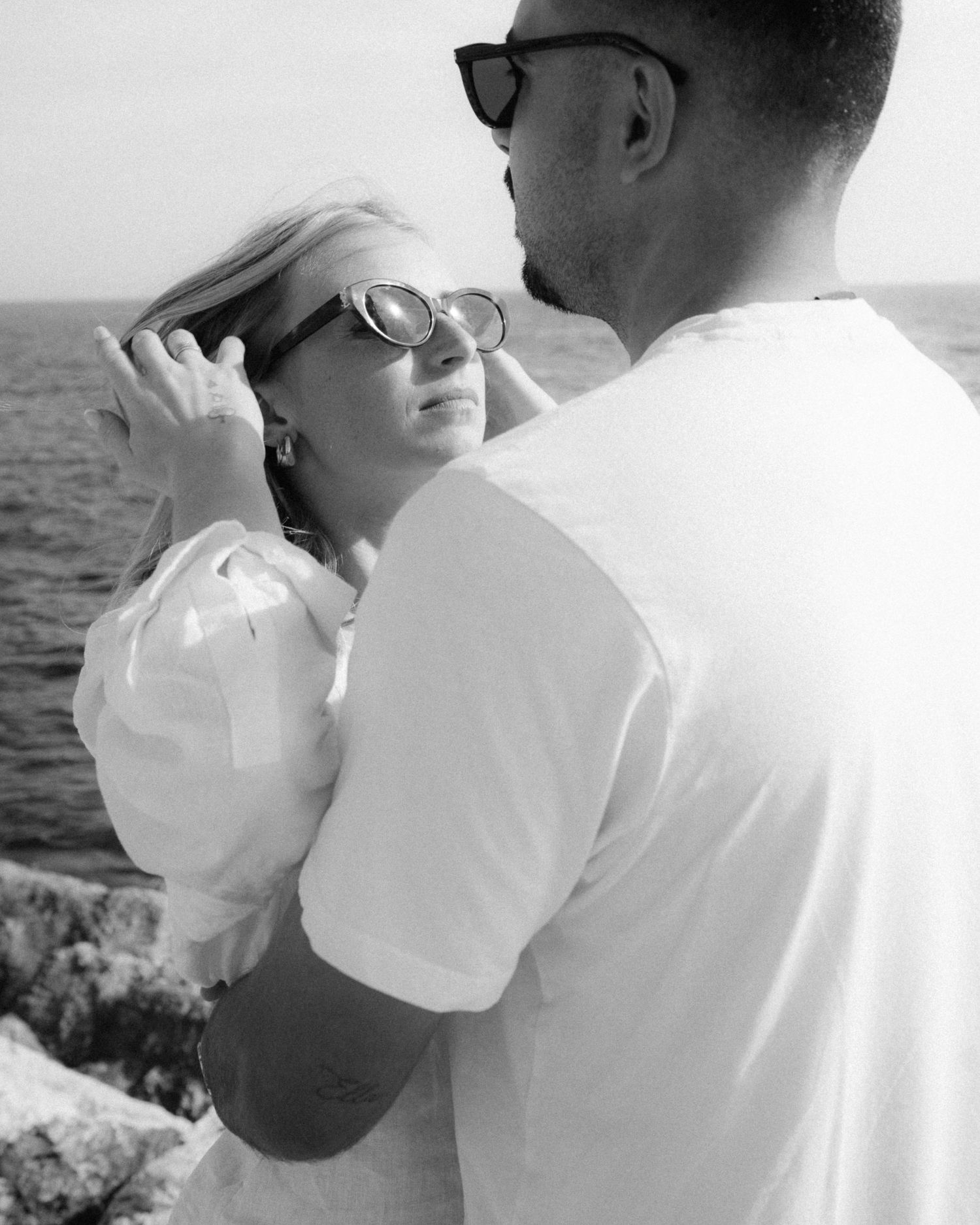 A romantic black and white photo series showing a couple embracing by the ocean.