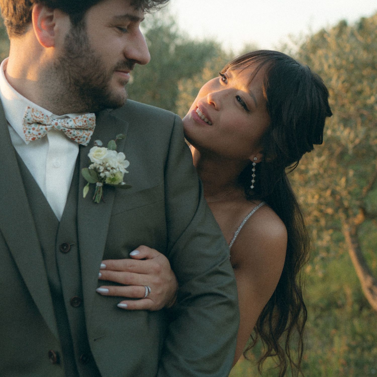 Romantic couple sharing intimate moments in a vineyard at sunset wearing formal wedding attire.