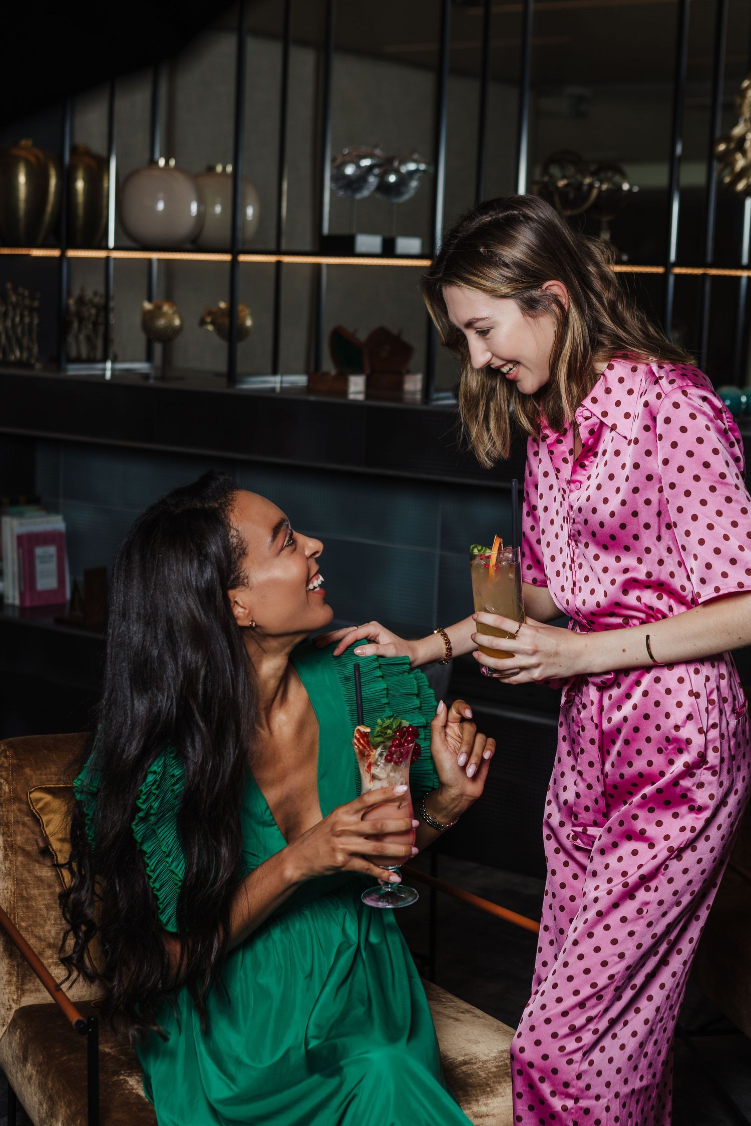 Friends sharing drinks and conversation in stylish bar interior.