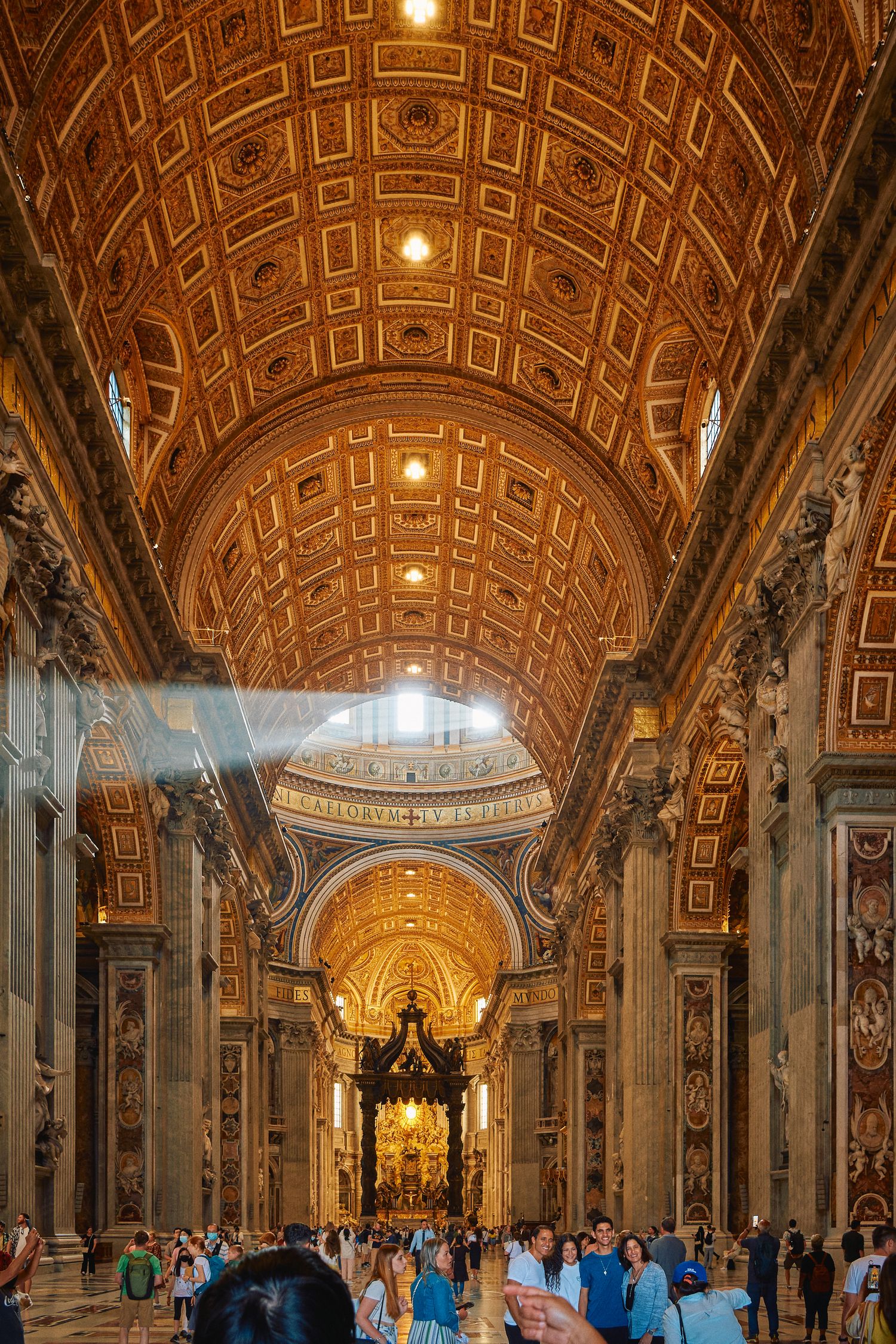 Sunlight streams through Saint Peter's Basilica's grand interior with tourists admiring the ornate architecture.