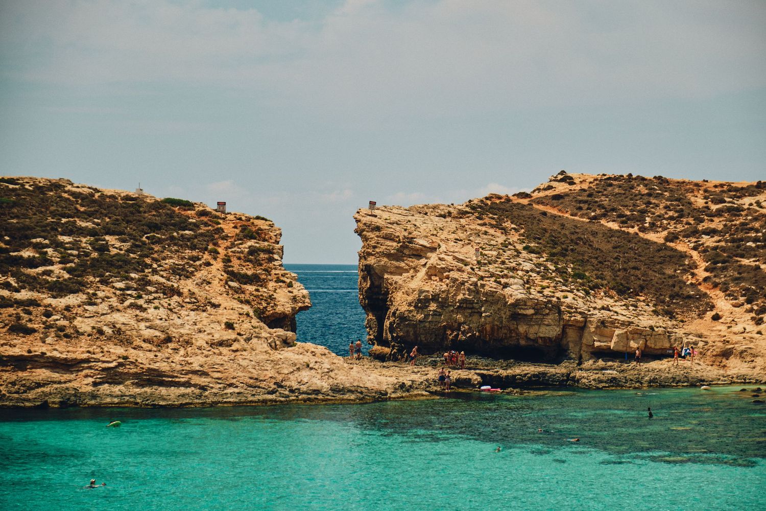 Natural rock arch formation over turquoise Mediterranean waters in Malta's coastline.
