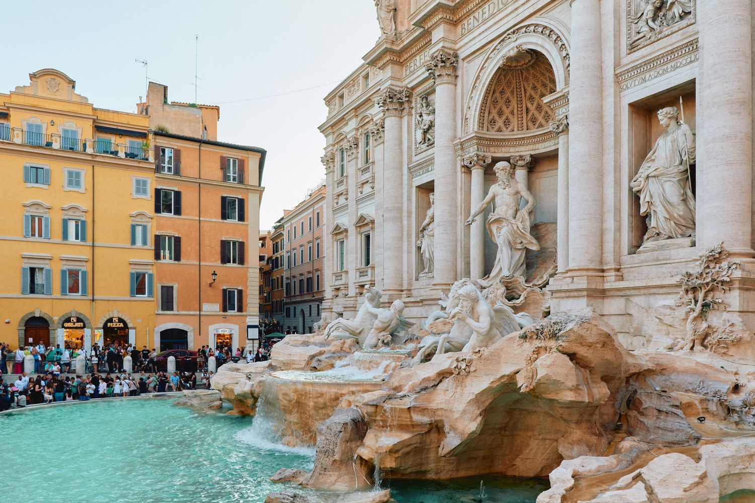 Side view of the Trevi Fountain showing intricate baroque sculptures and turquoise water.