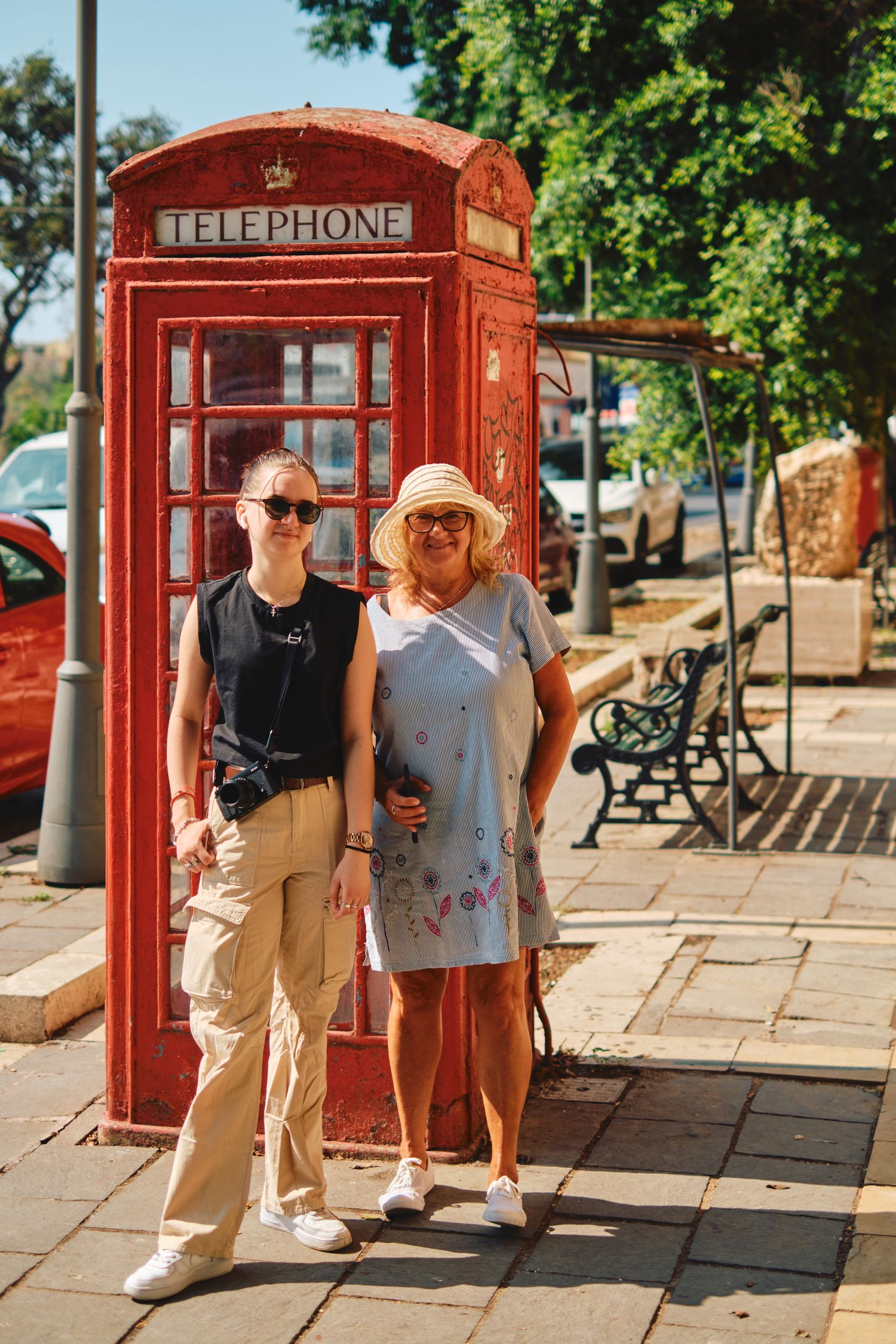 Classic red British telephone booth on a sunny street.