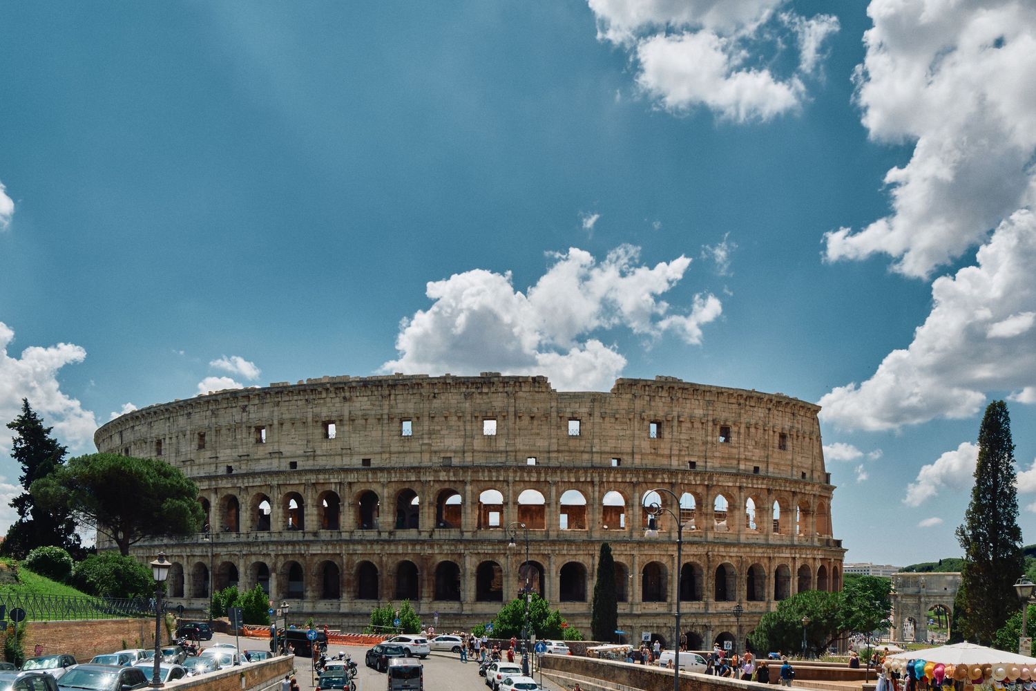 Ancient Roman Colosseum exterior view with blue sky and white clouds in Rome, Italy.