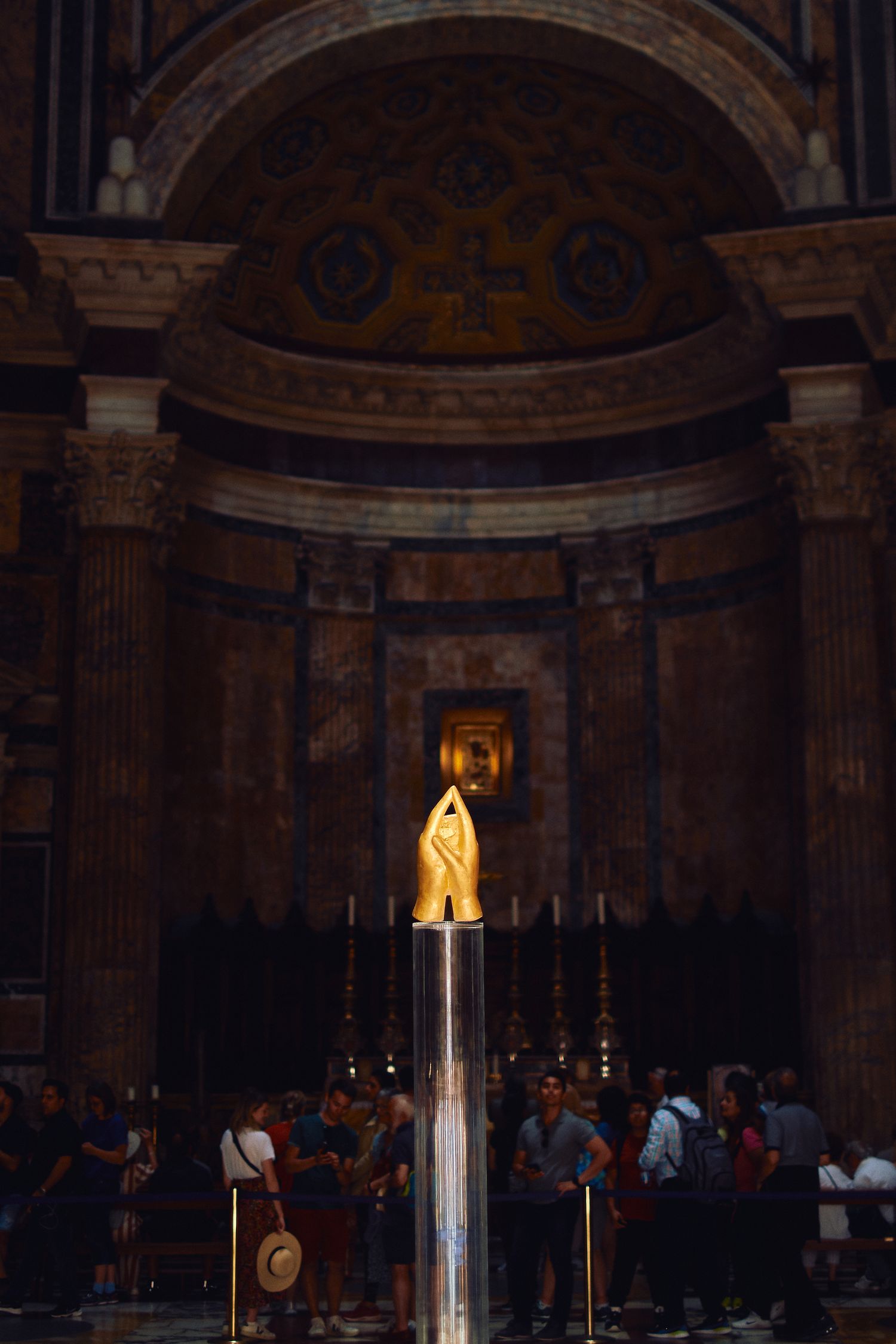 Golden statue illuminated in an ornate church alcove with visitors gathered below.