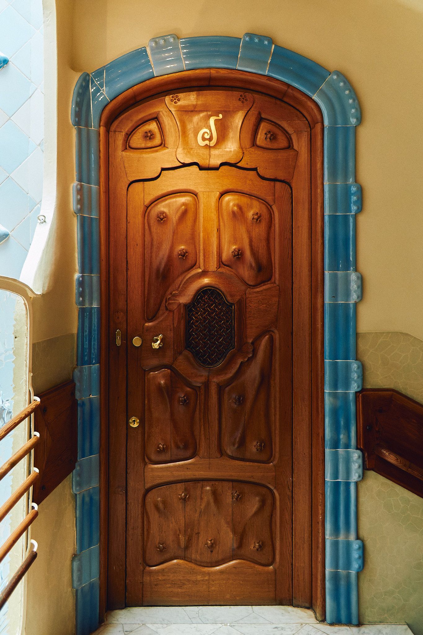 Ornate wooden Art Nouveau door with blue ceramic tile frame in Casa Batllo, Barcelona, designed by Antoni Gaudi.