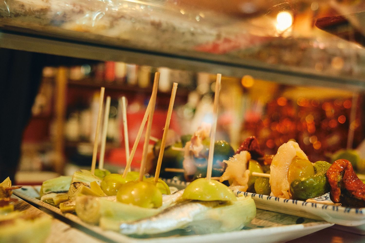 Close-up of Spanish tapas with toothpicks arranged on serving platters.