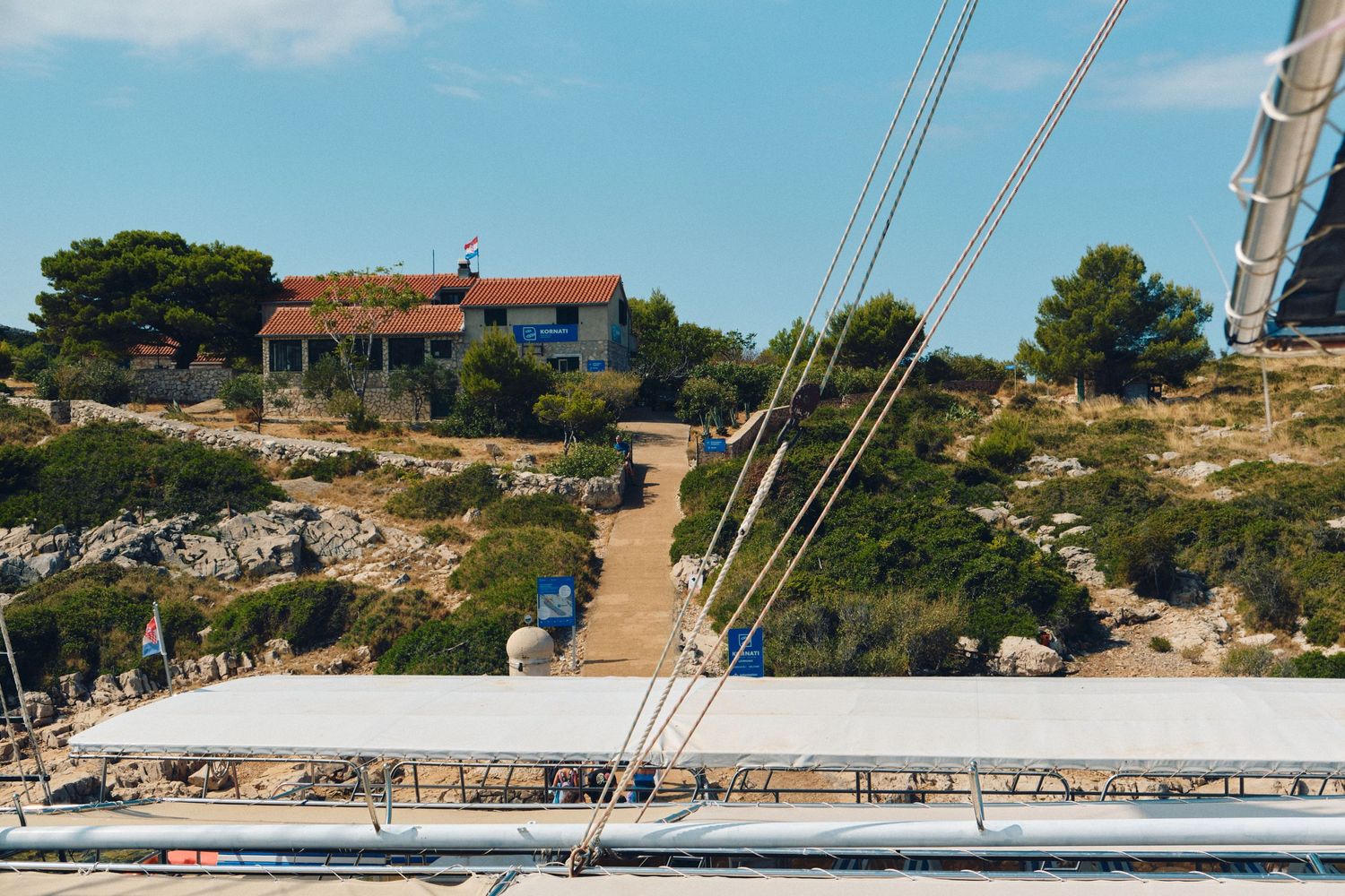 Coastal villa perched on rocky terrain viewed from boat deck with ropes in foreground.