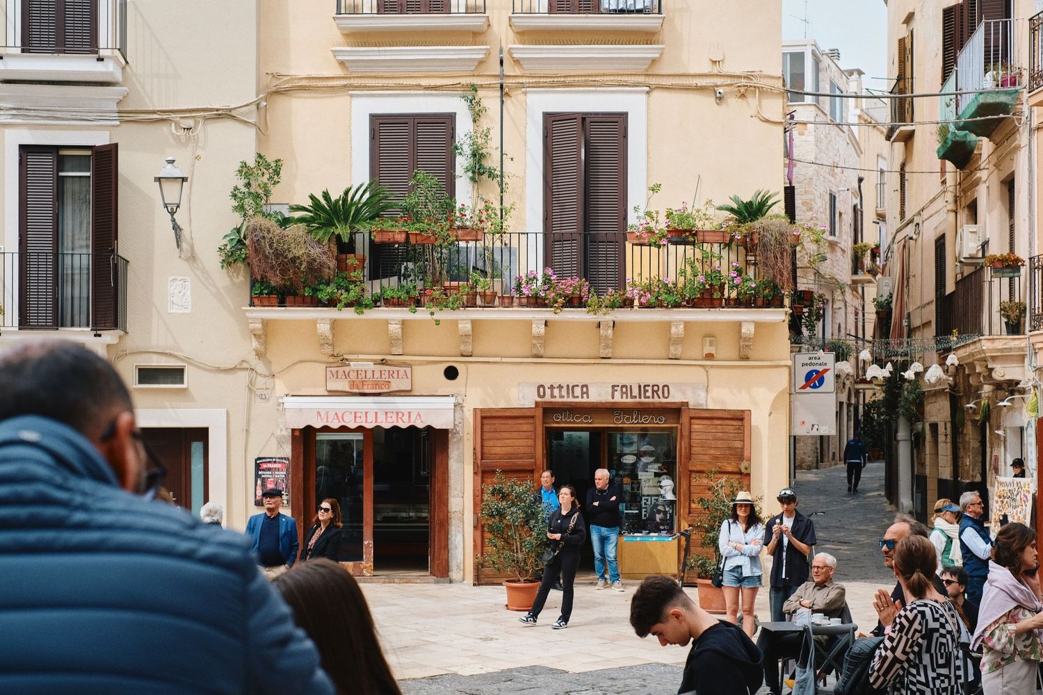 Lively Mediterranean street corner with a cafe and decorative balconies above.