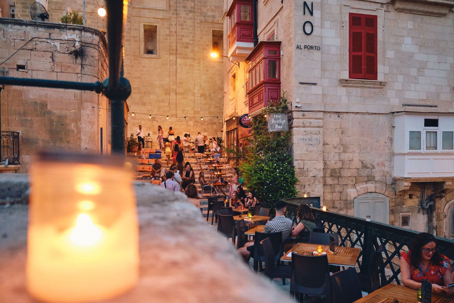 Candlelit outdoor dining area along stone walls with traditional architecture in Malta.